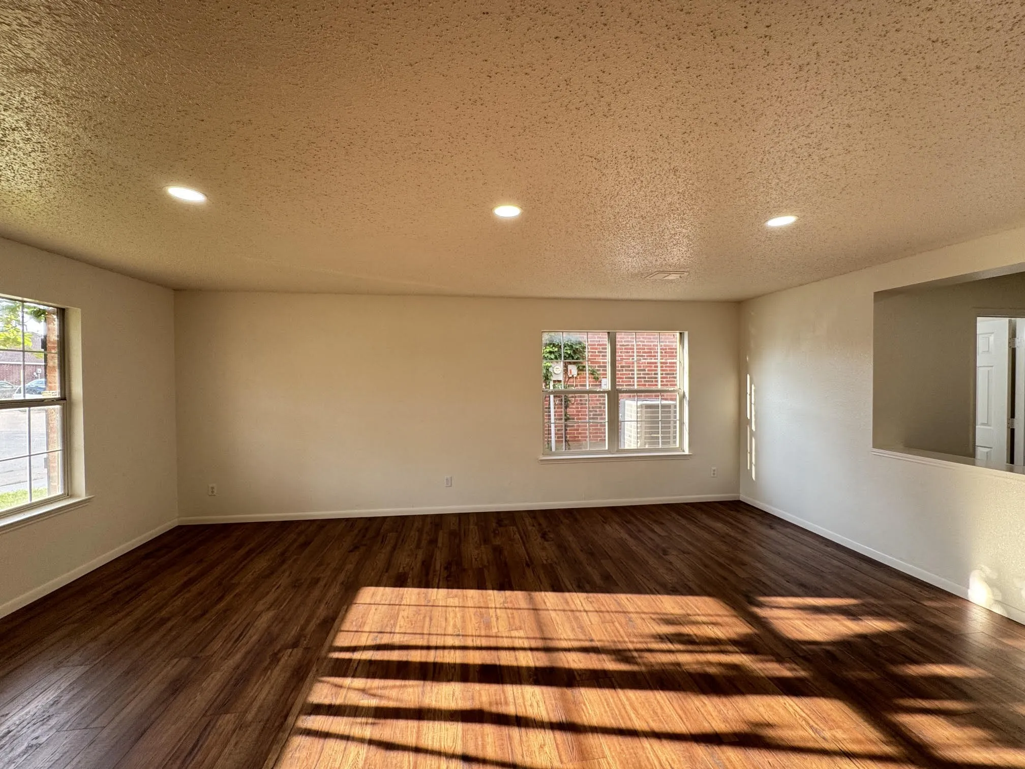 Spacious interior room featuring wood-finish flooring, recessed lighting, and multiple windows