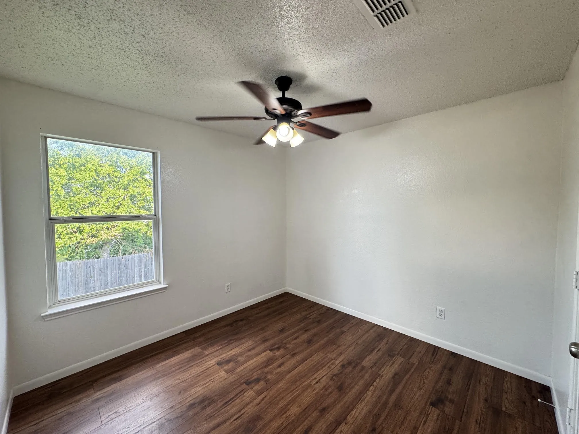 Bedroom featuring wood-finish flooring, white walls, and a ceiling fan with integrated lighting