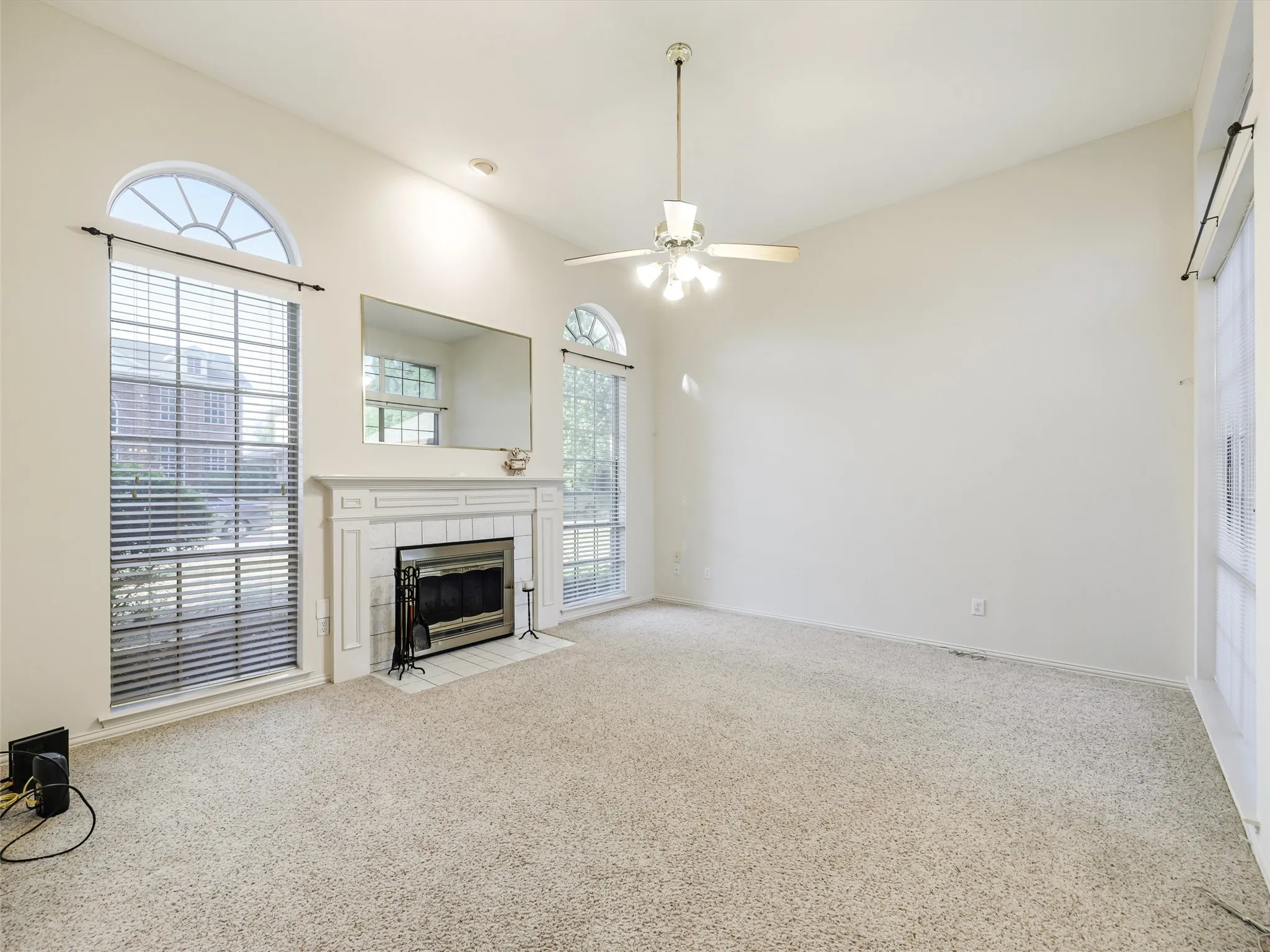 Living area featuring a fireplace with a white mantel, arched windows, and vaulted ceilings