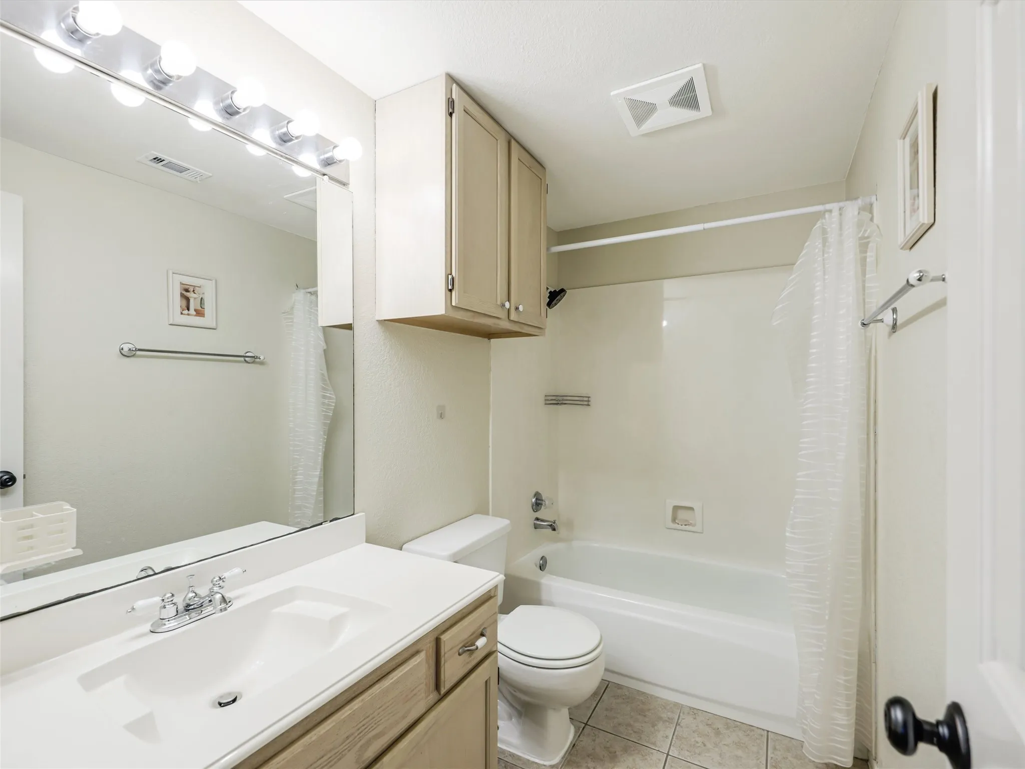 Bathroom featuring a vanity with integrated sink, chrome-finish faucet, full-width mirror, and overhead lighting