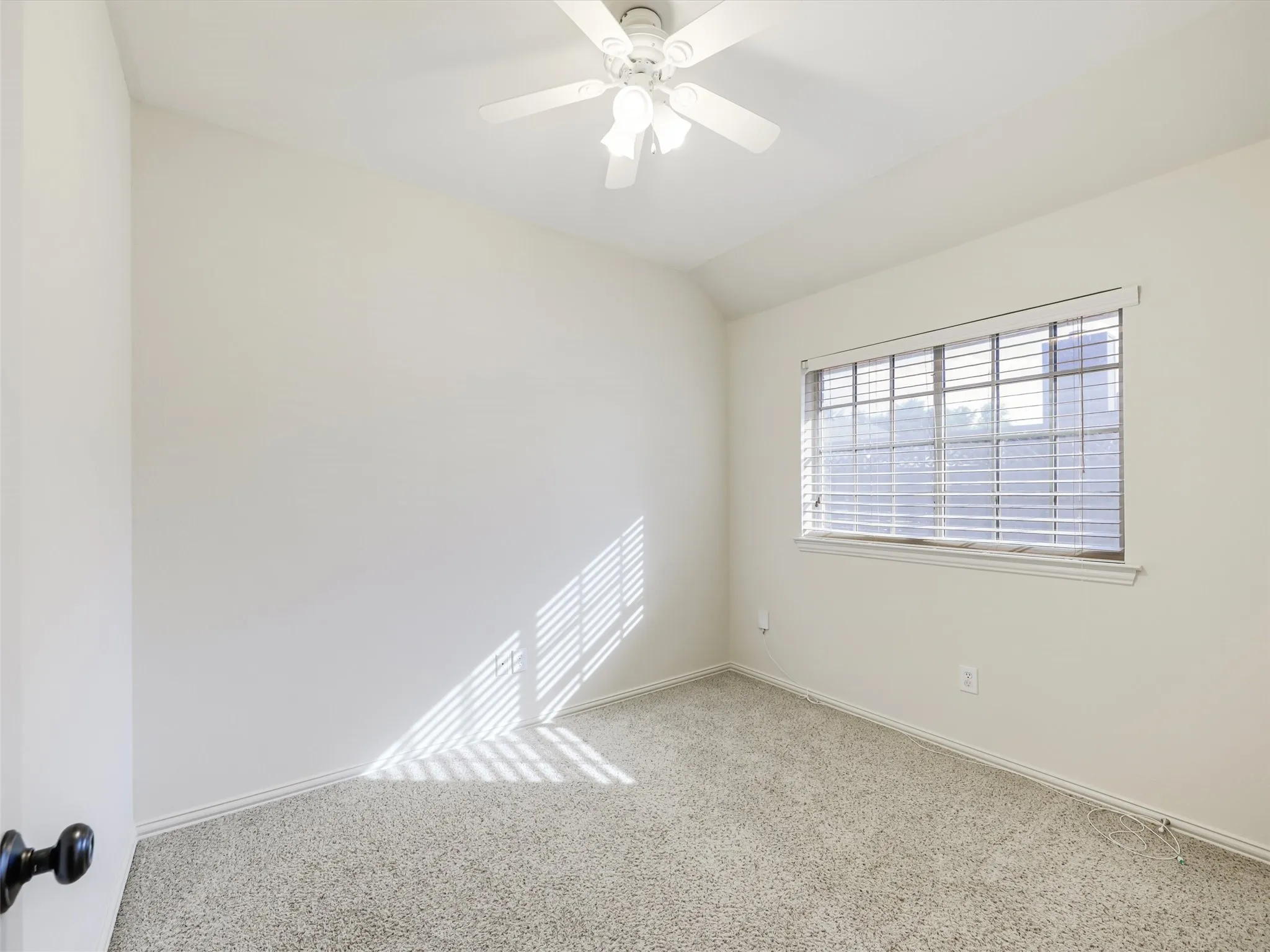 Wall-to-wall carpeting, window with blinds, ceiling fan with light fixture, and white walls