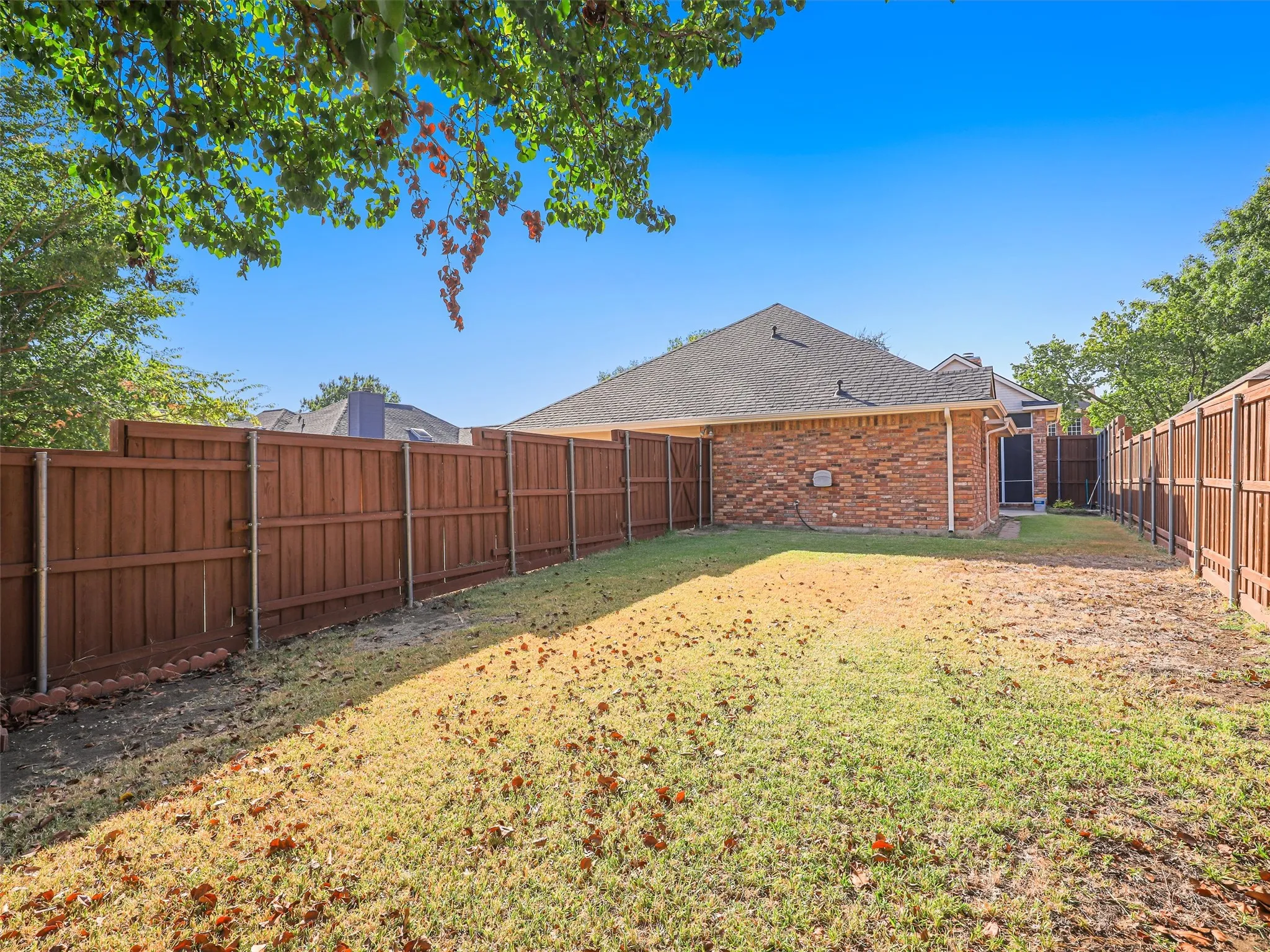 Expansive fenced backyard featuring a brick exterior and a privacy fence