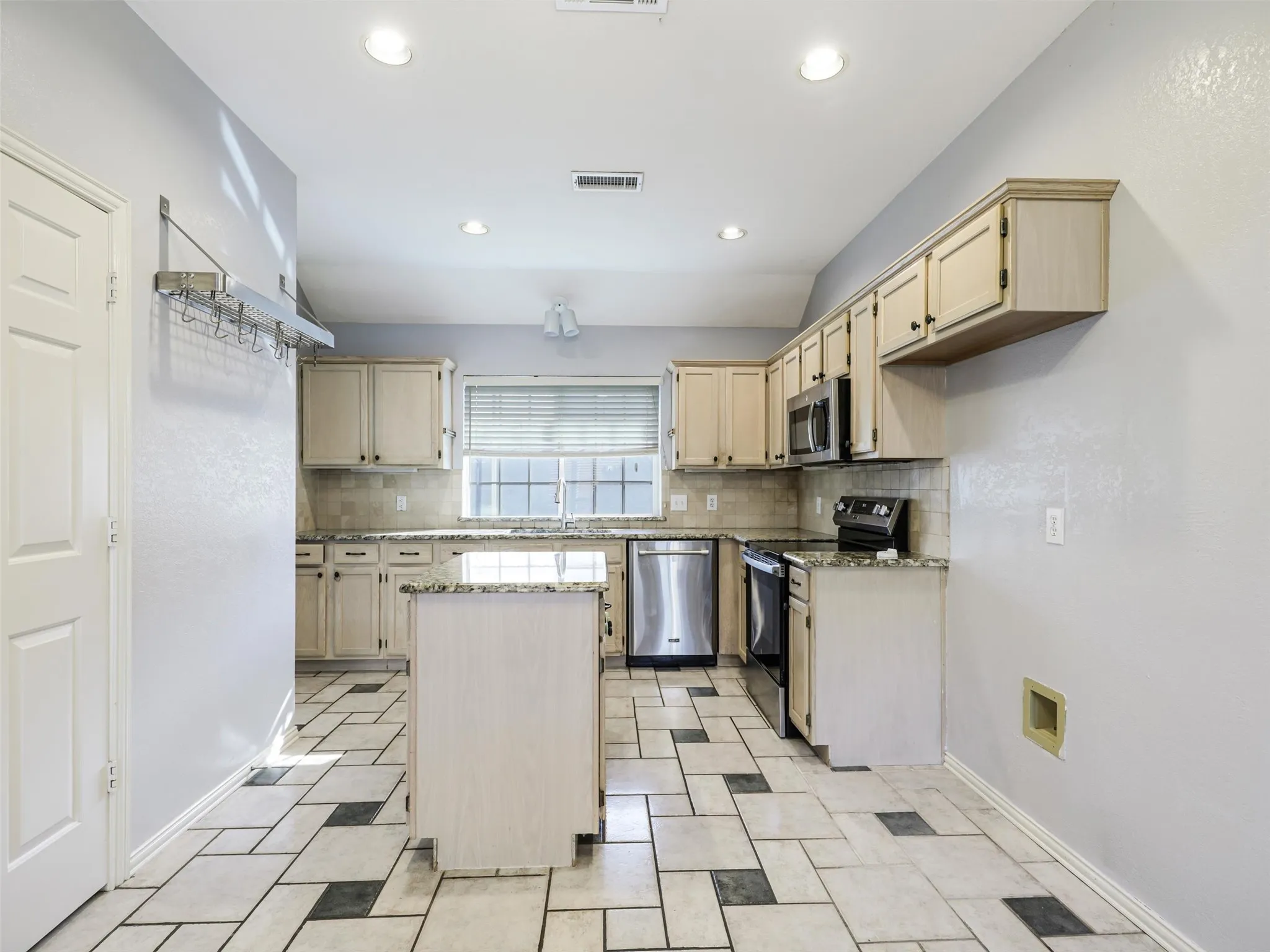 Kitchen featuring an island, light-toned cabinetry, stainless steel appliances, recessed lighting, and a patterned tile floor