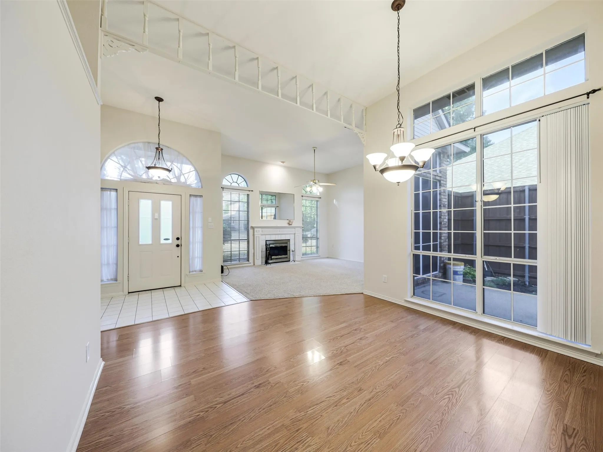 Vaulted ceilings, wood-finish flooring, white tile entry, decorative interior archway, and a fireplace with a mantel