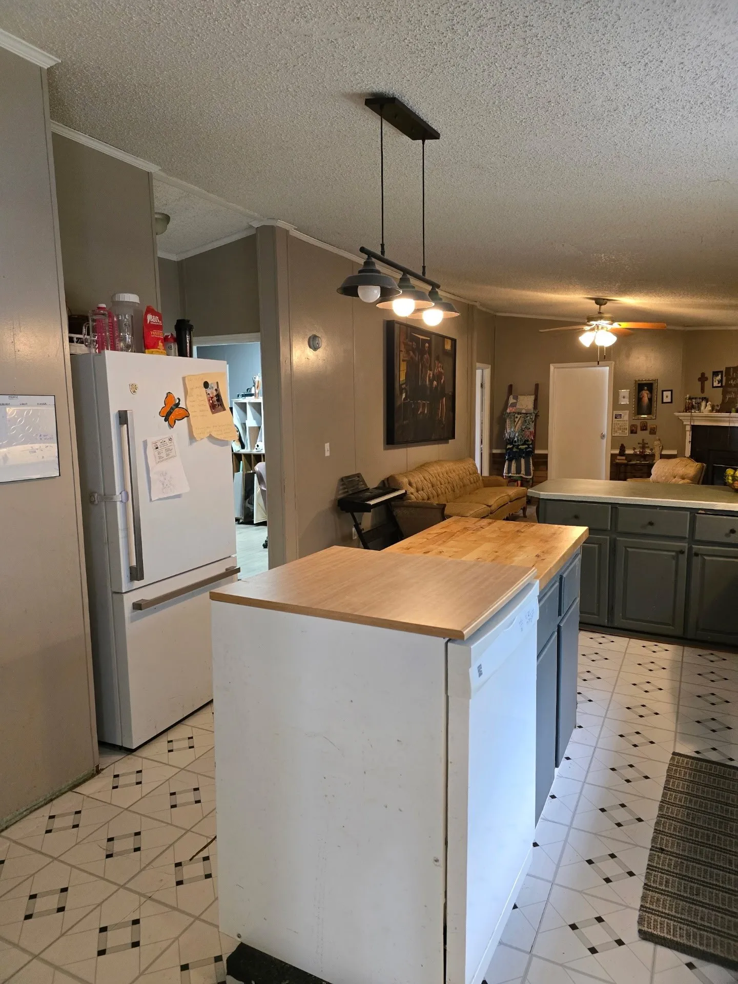 Kitchen featuring an island with wood-finish countertop, pendant lighting, and patterned flooring