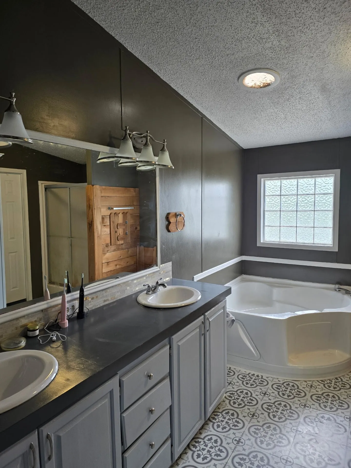 Dual vanity with light gray cabinetry, dark countertops, and undermount sinks