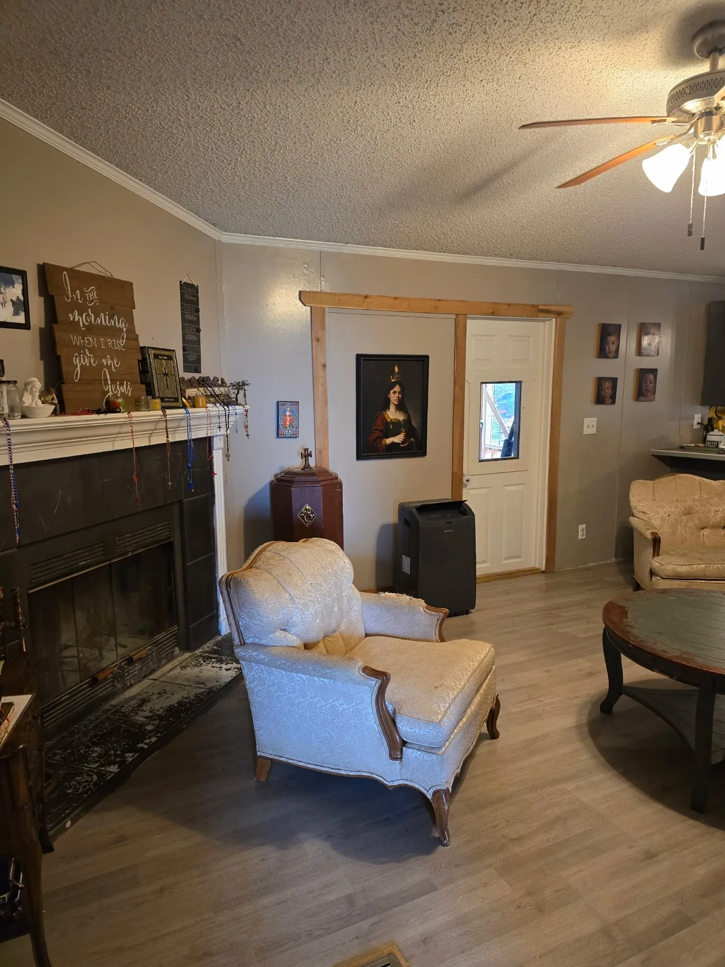 Built-in fireplace with a stone hearth, wood-finish flooring, a ceiling fan, crown molding, and a solid exterior door with a window insert