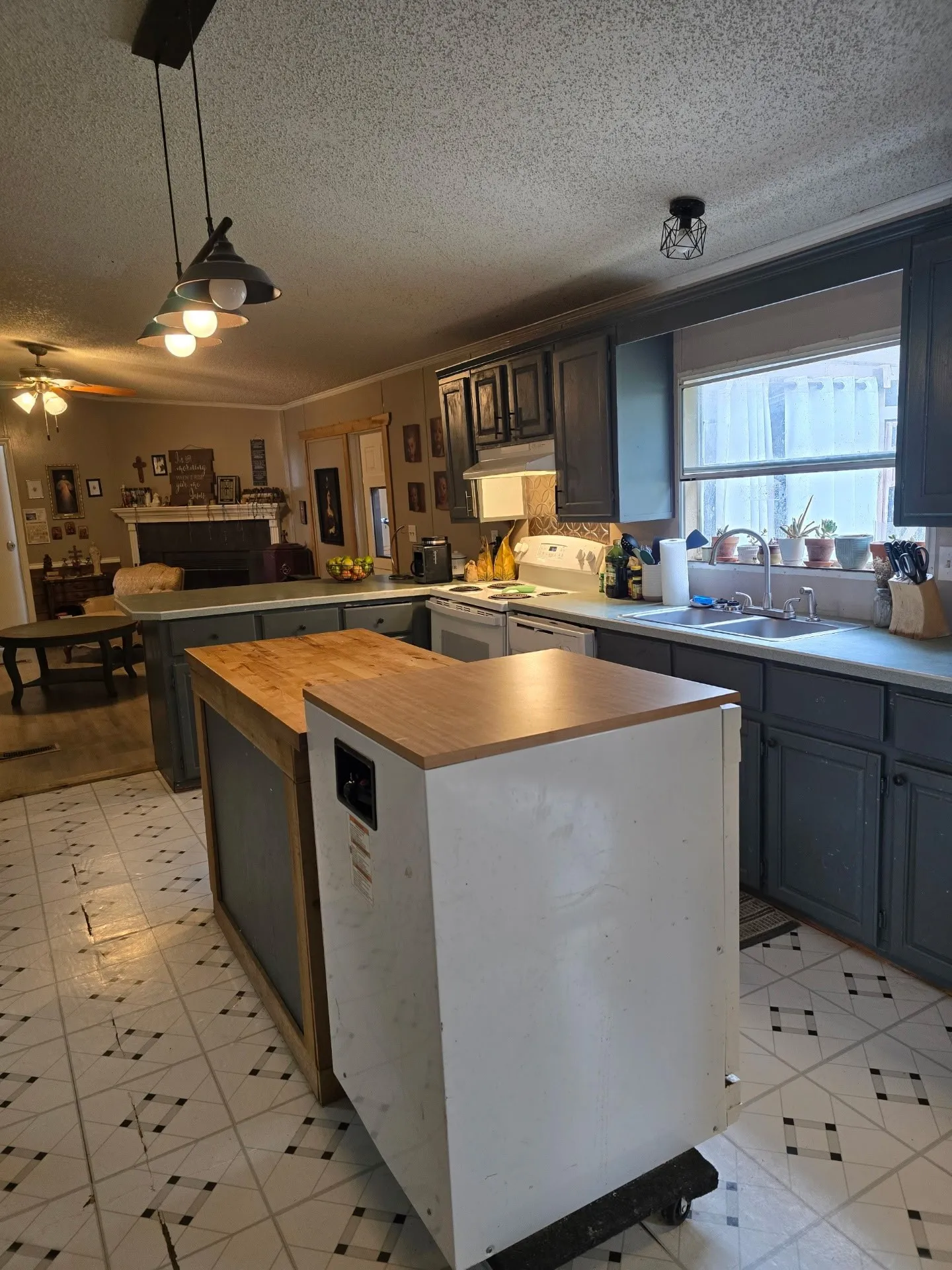 Kitchen featuring dark-toned cabinetry, light countertops, a stainless steel sink, and a tiled backsplash