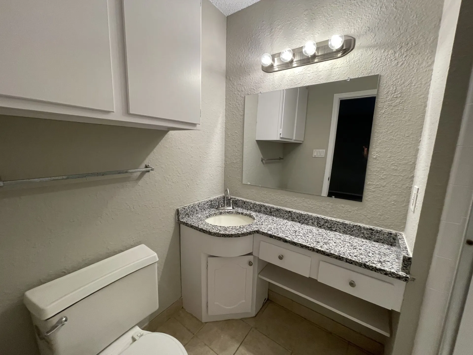 Vanity with a granite-style countertop, integrated sink, and white cabinetry