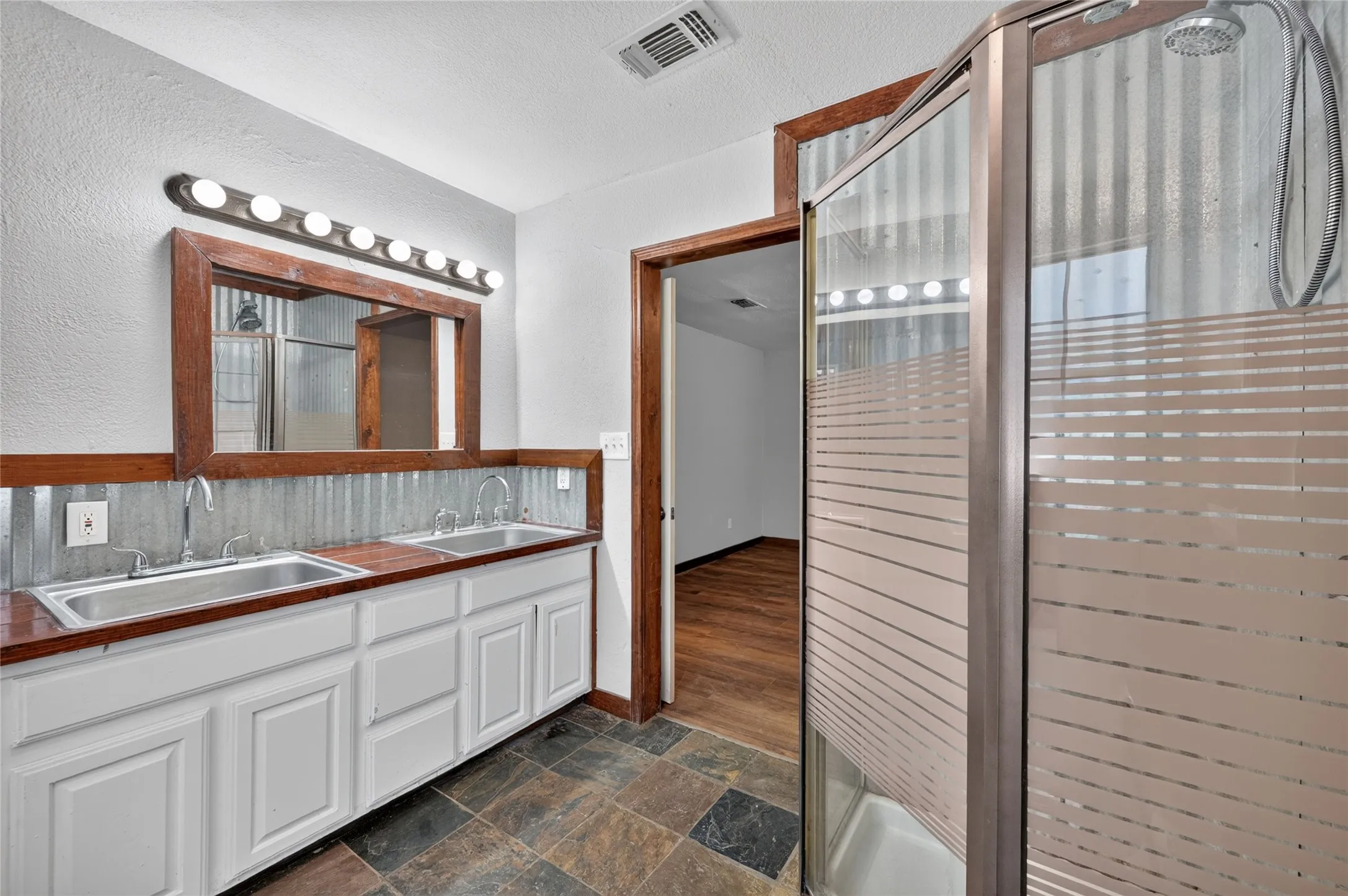 Dual vanity with integrated sinks, wood-finish countertop, and white cabinetry