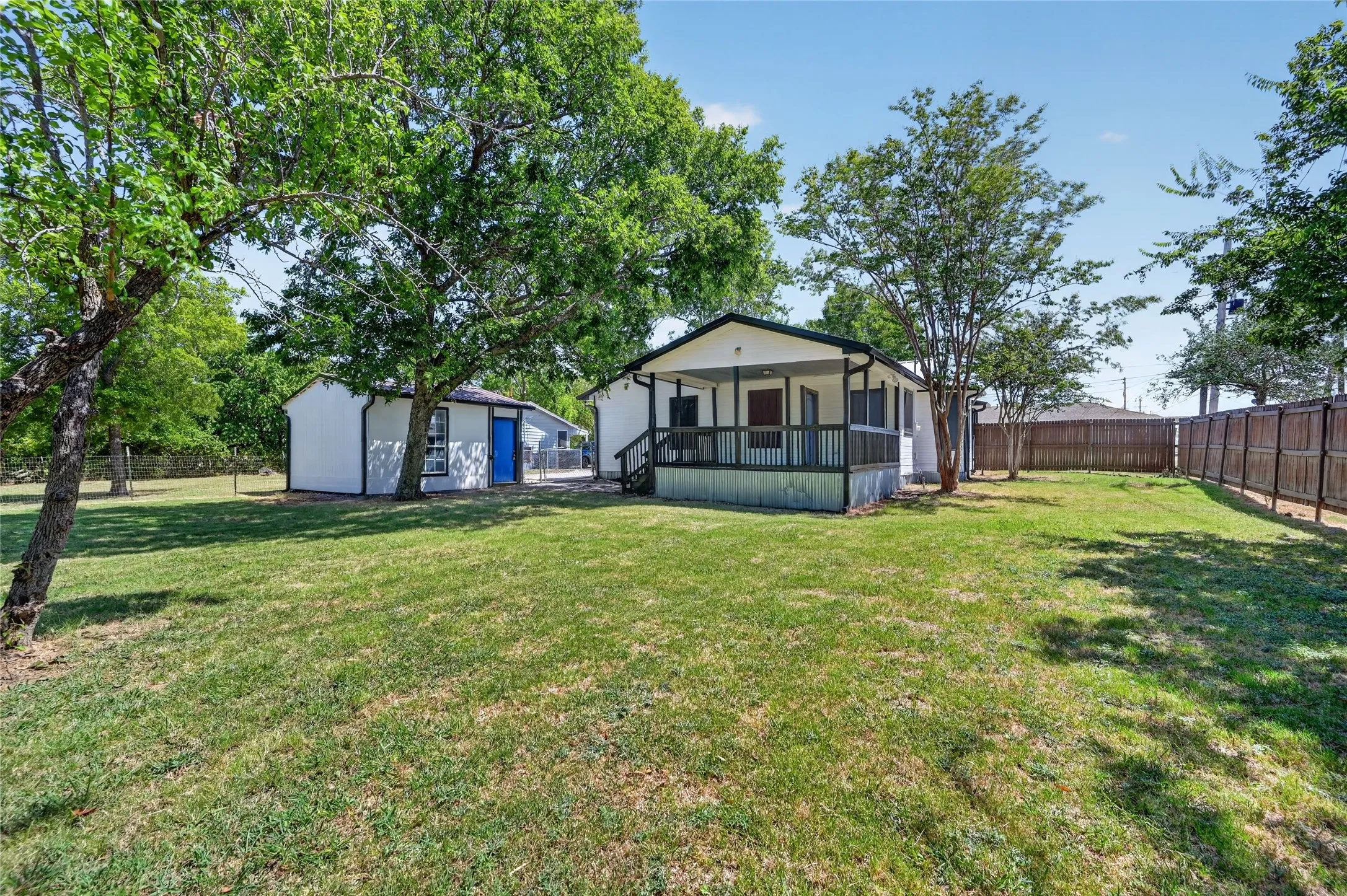 Expansive lawn with mature trees and a wood privacy fence