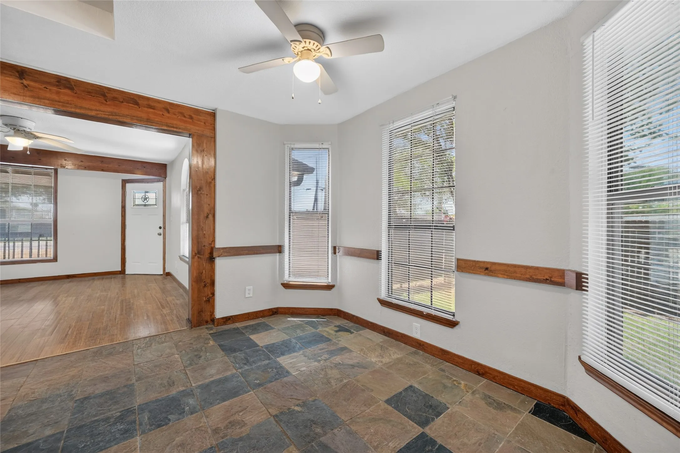 Multi-toned tile flooring, three large windows, a ceiling fan, and wood trim accents throughout