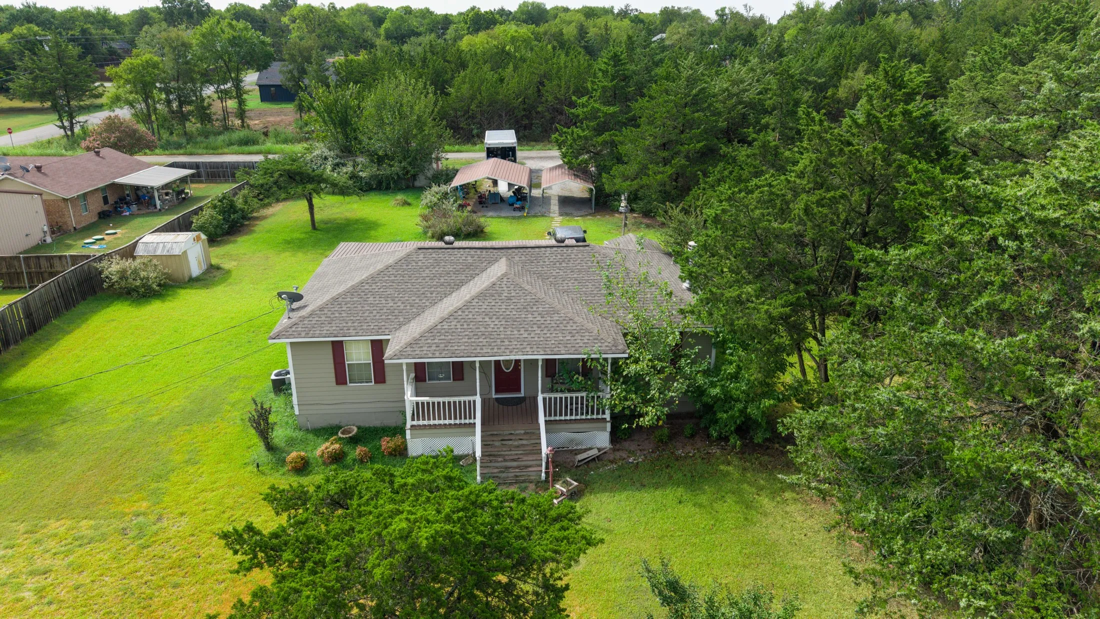 Single-story residence featuring a covered front porch with white railings, a gray shingle roof, and a red front door