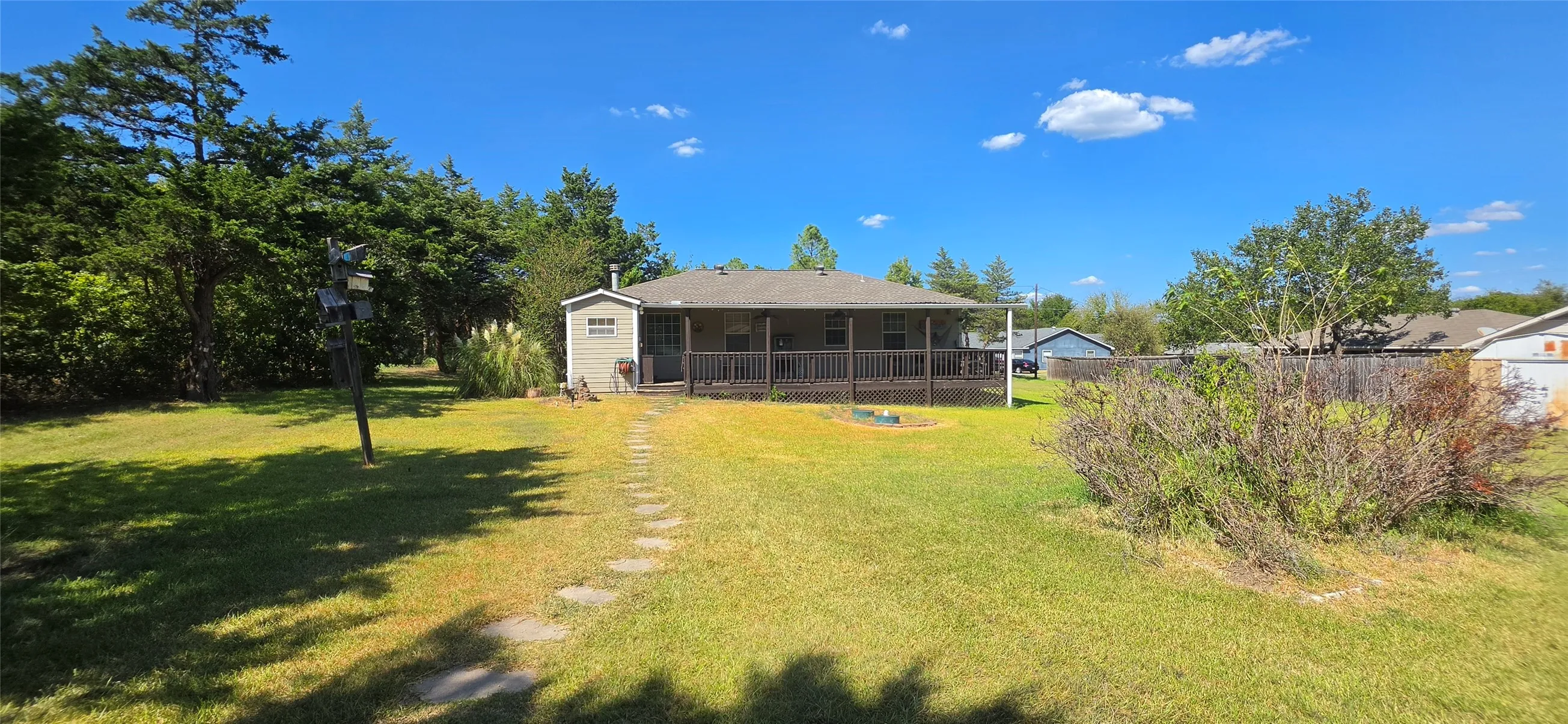 Expansive grassy yard with a stone path leading to a wide rear deck