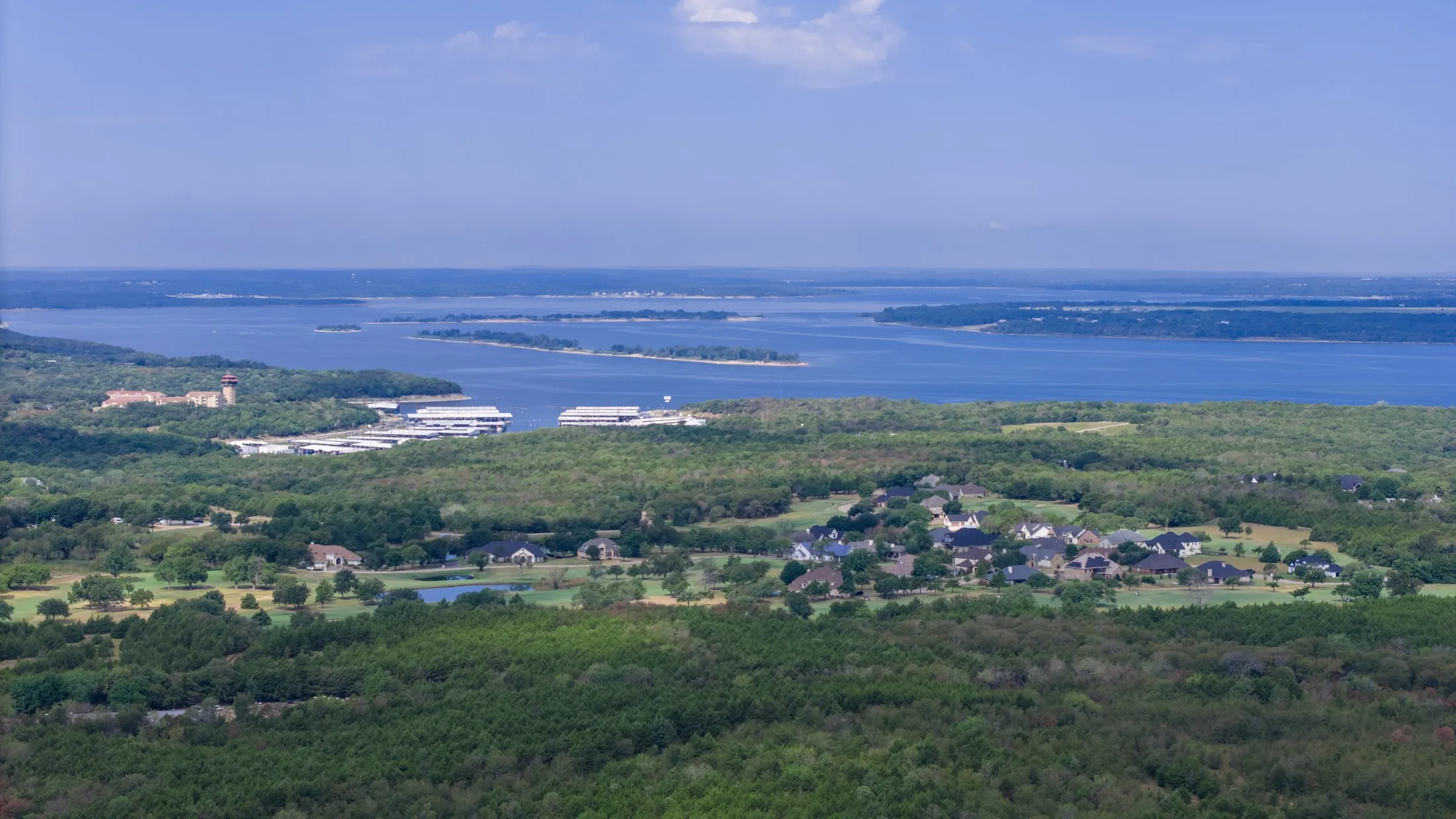 Expansive water body, verdant treeline, residential cluster, and multiple islands