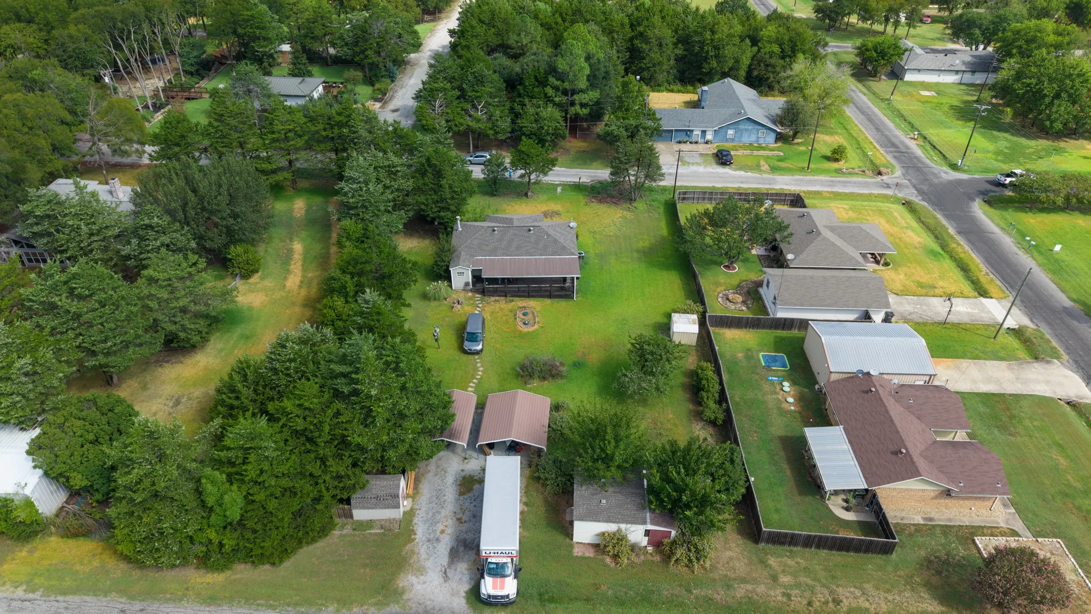 Expansive lot with lush green landscaping, mature trees, and a detached structure