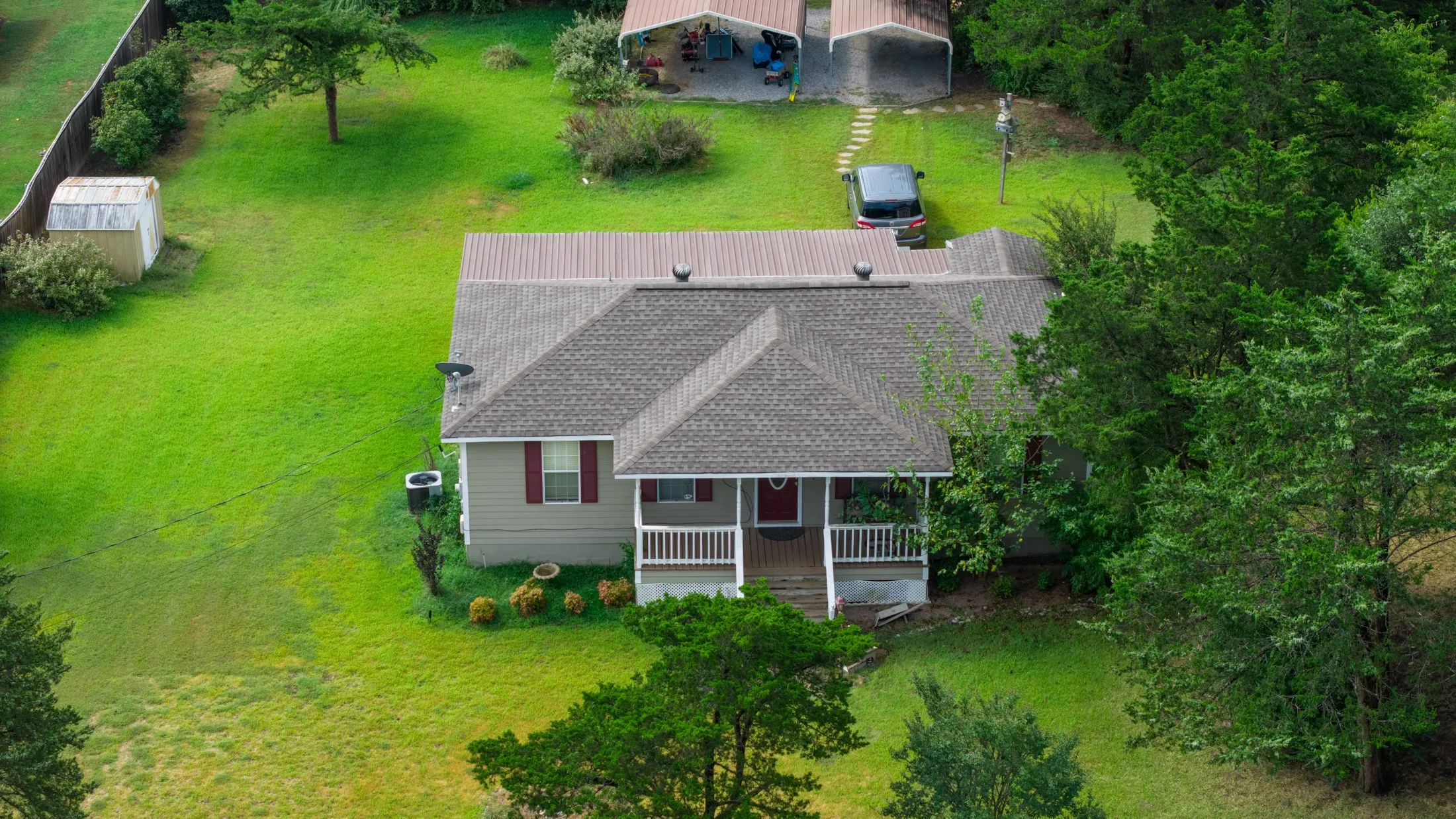 Ranch-style exterior with a covered front porch, asphalt shingle roof, and detached metal carport