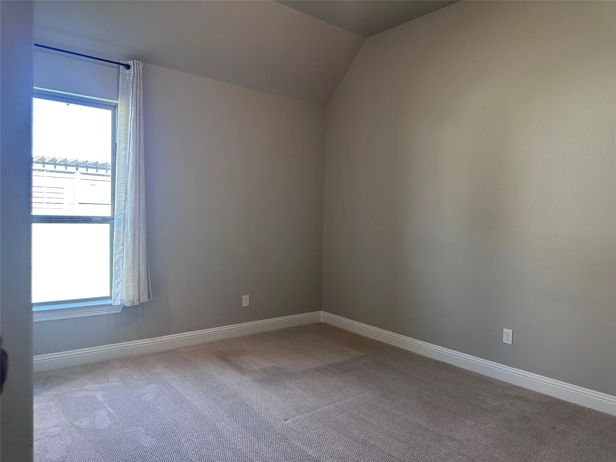 Carpeted flooring, neutral wall paint, and a window with a curtain rod