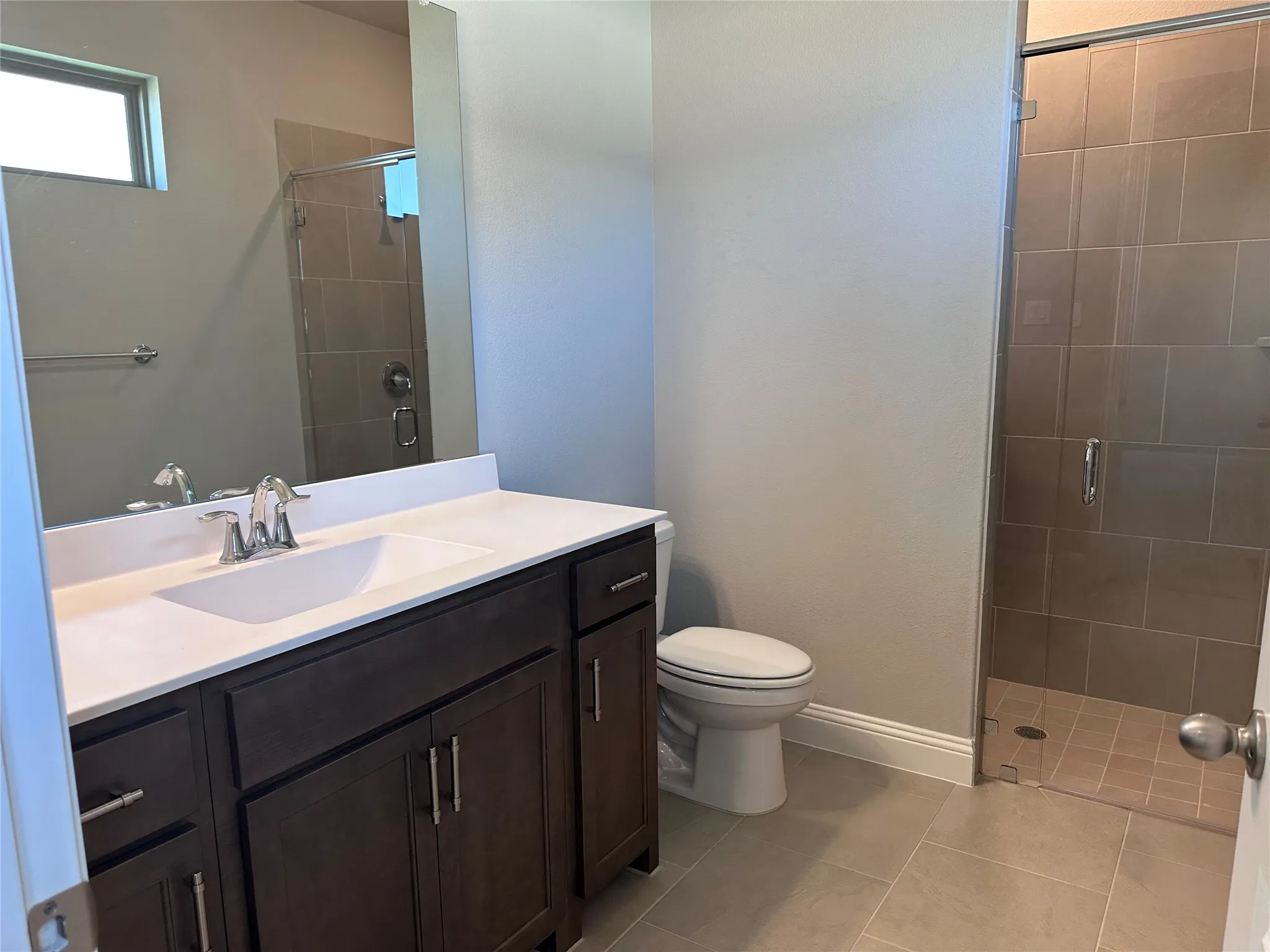 Bathroom with dark wood-finish vanity, integrated sink, and chrome fixtures
