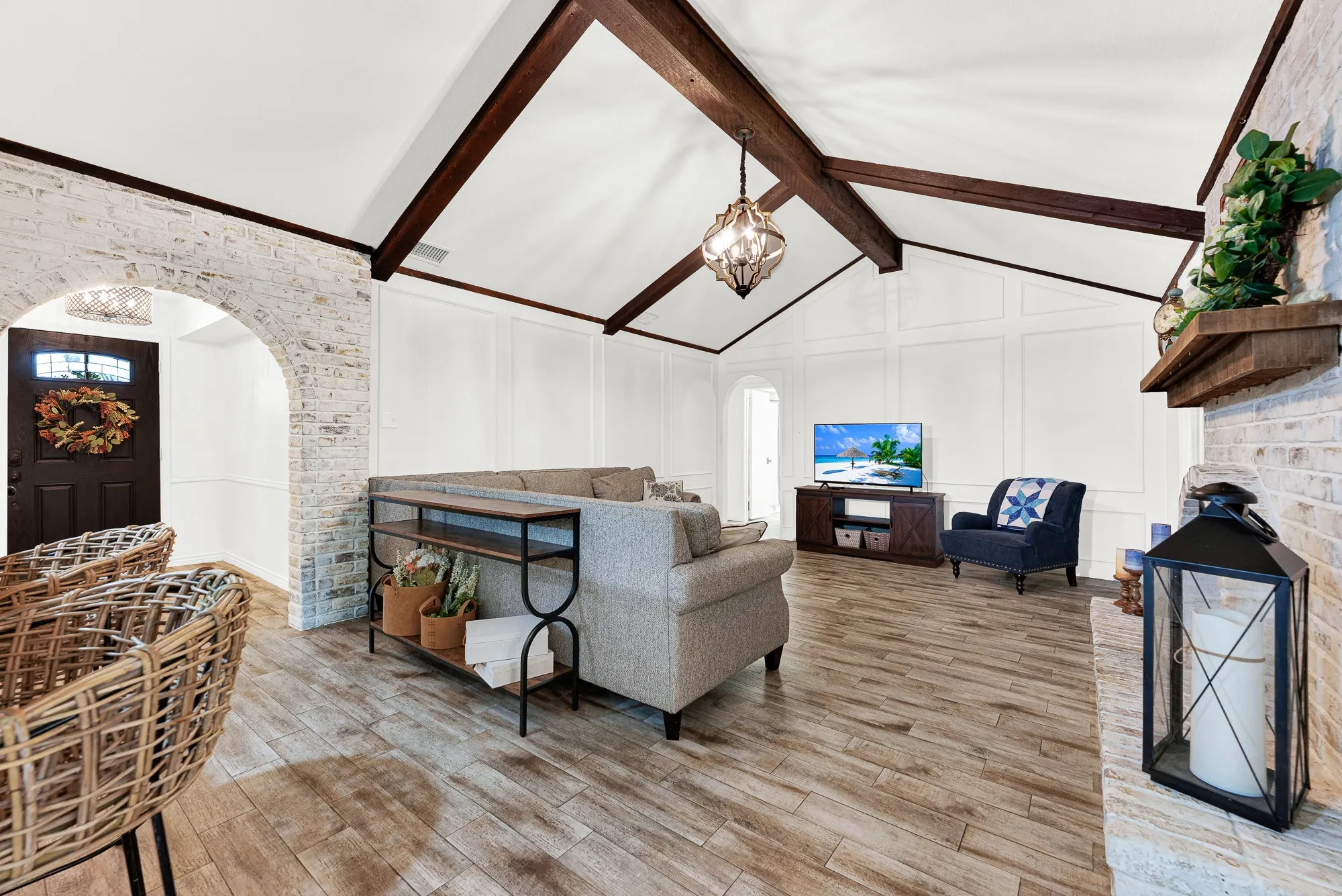 Dramatic vaulted ceilings with dark wood beams, a statement orb pendant, and clean wall paneling highlight this expansive main gathering room. It is a fantastic space to unwind with family for weekend movie marathons or host lively game nights.
