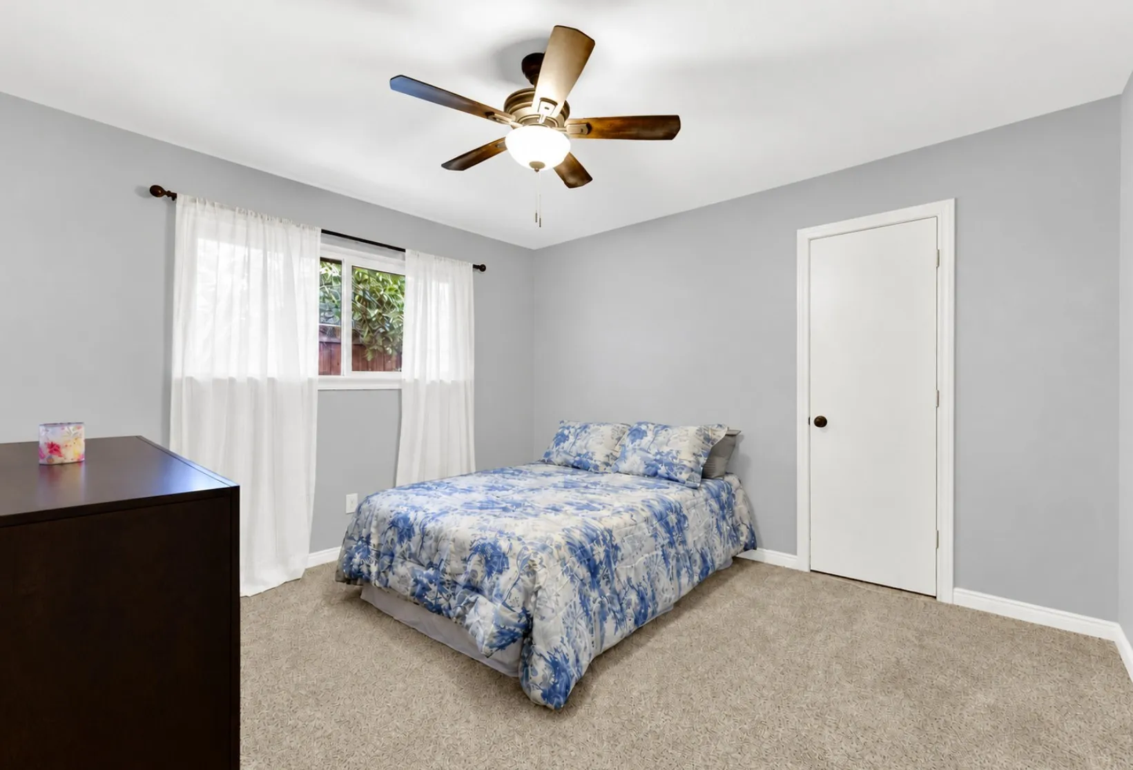 Painted in a subtle hue, this bright secondary bedroom enjoys soft natural daylight through double windows. Neutral plush carpeting, a wide storage closet, and a overhead fan make it a ready-to-use guest room or nursery.
