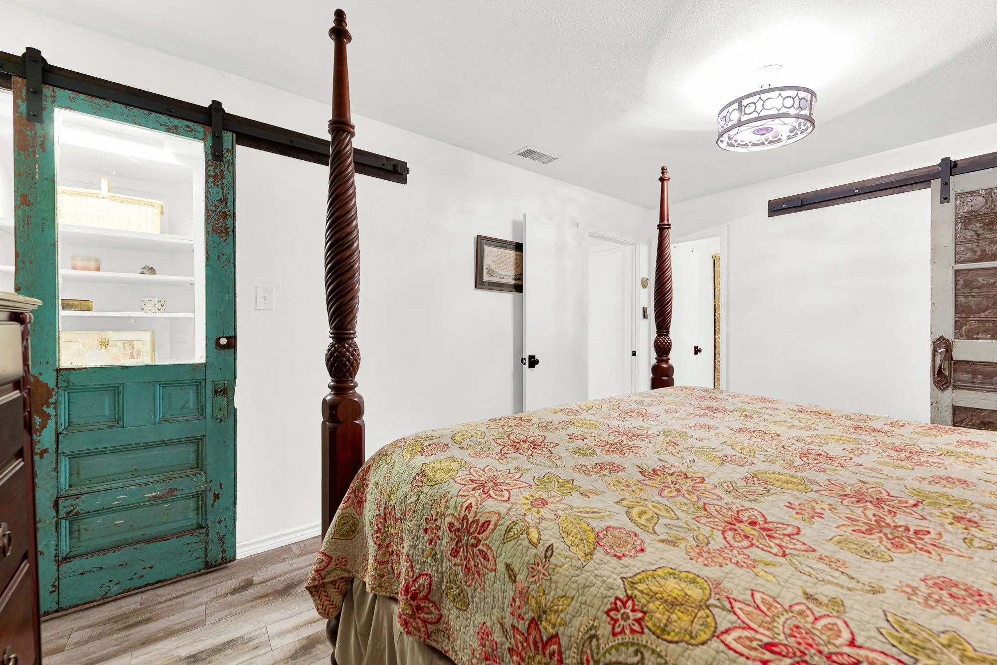 A vibrant teal rustic sliding door adds a playful splash of farmhouse character while concealing generous built-in display cabinet and desk. Clever architectural details make this bedroom delightful.