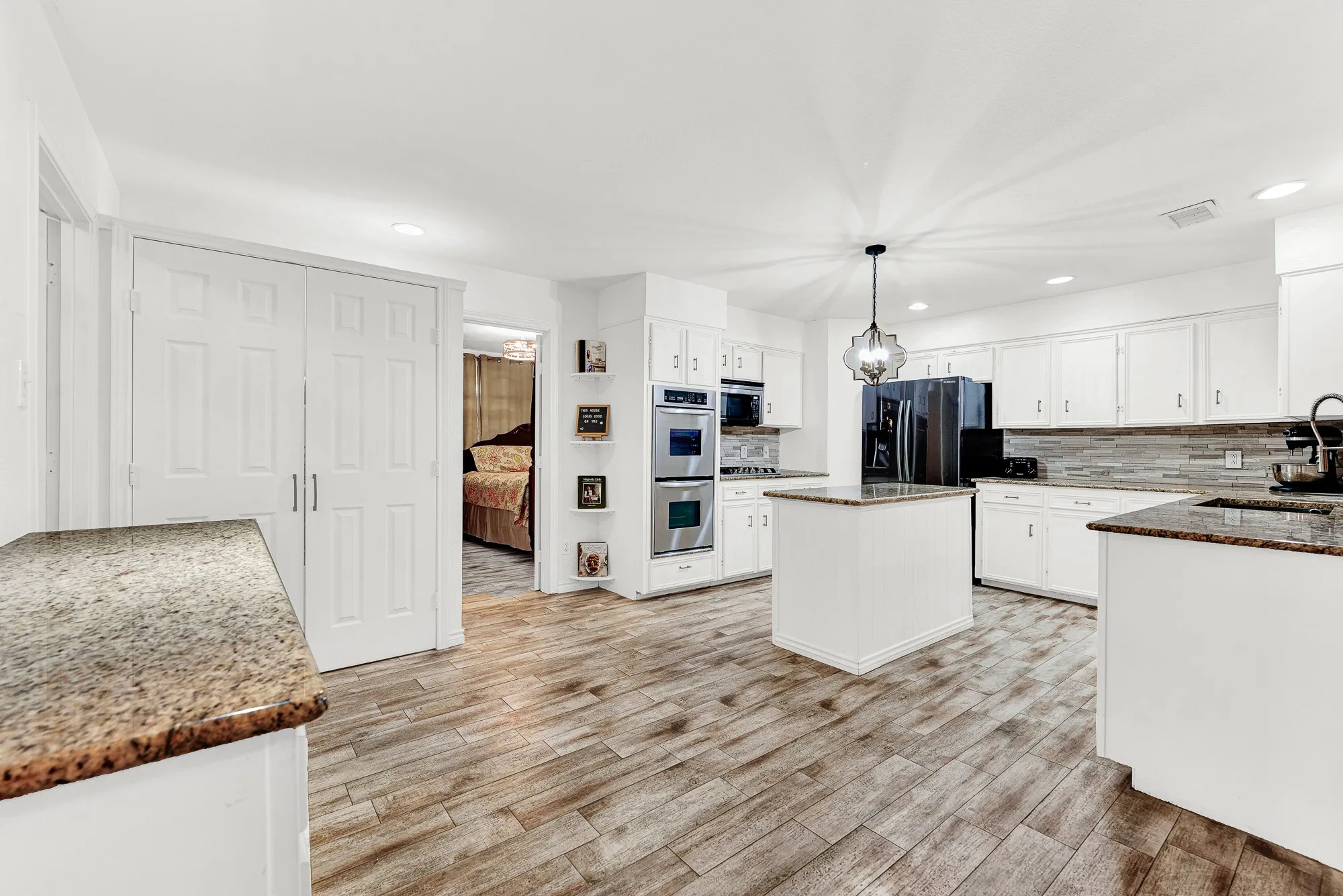 This wide perspective highlights the seamless flow between the completely renovated kitchen, central island, and neighboring living spaces. You will love how easily family members can grab snacks or move through the home during busy morning routines.