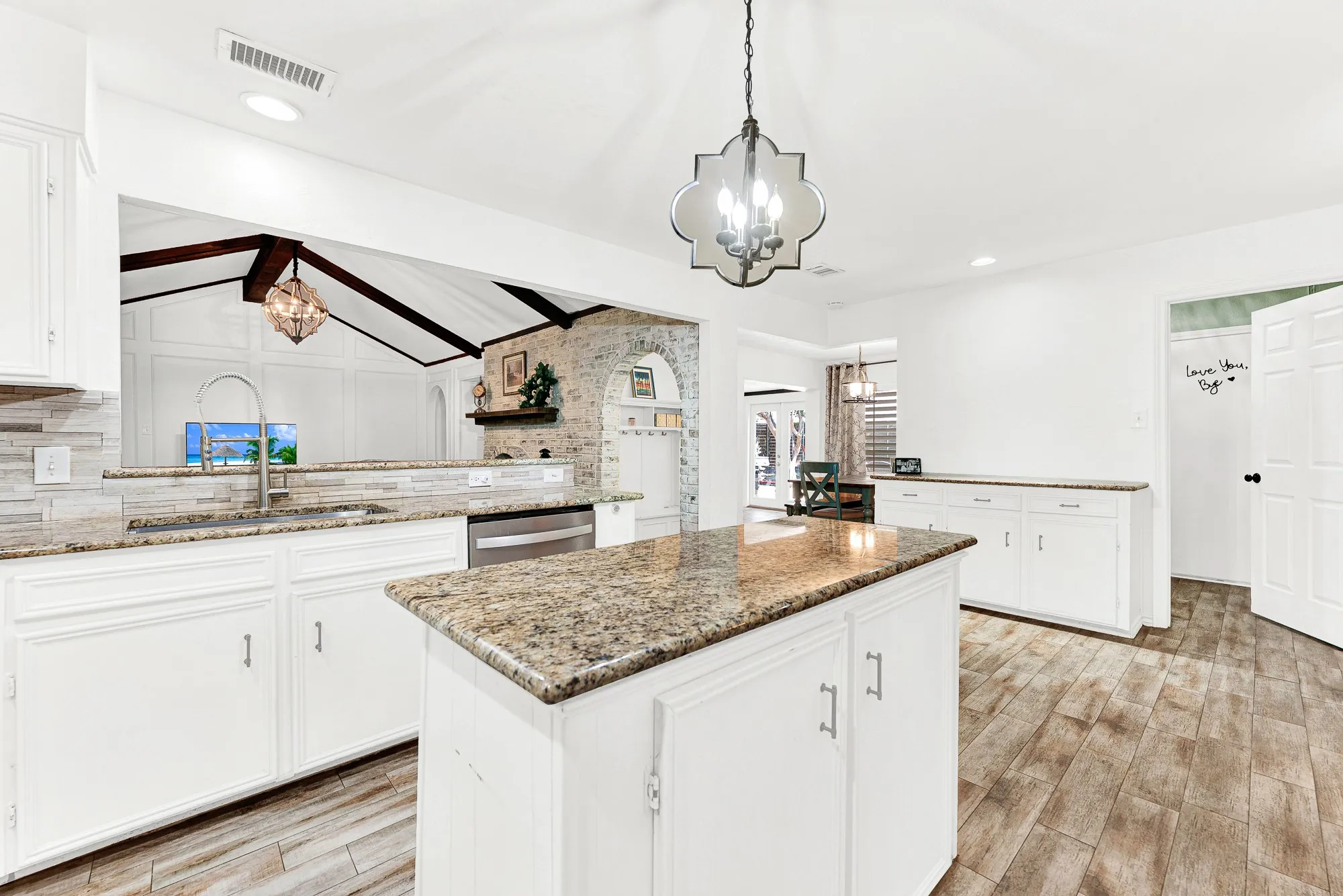 Looking back toward the living area, this shot displays the kitchen sink peninsula, additional side cabinetry, and open wall cutout. You can easily watch the kids play or stay connected to movie night chatter while tidying up after dinner.