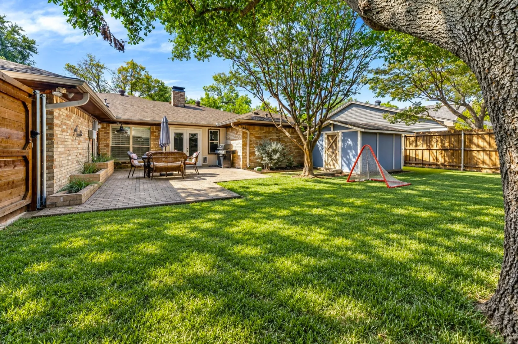 Tucked behind the home, an expansive paved patio creates a private oasis for outdoor dining and weekend gatherings. Mature shade trees keep the backyard cool, while a detached storage shed offers convenient space for lawn equipment and outdoor gear. Digitally enchanced by AI.