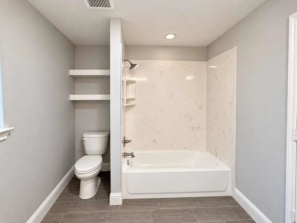 Main home bathroom with a tub and shower combination and open shelving.