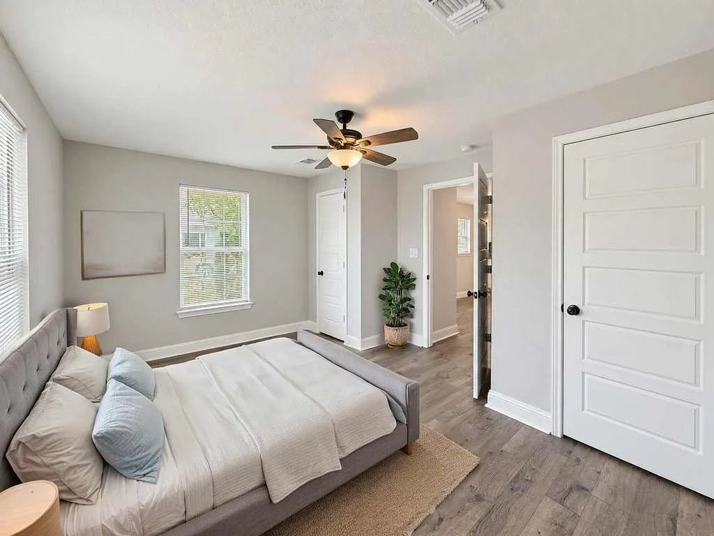 Another main home bedroom view with windows and laminate flooring. Virtually staged.