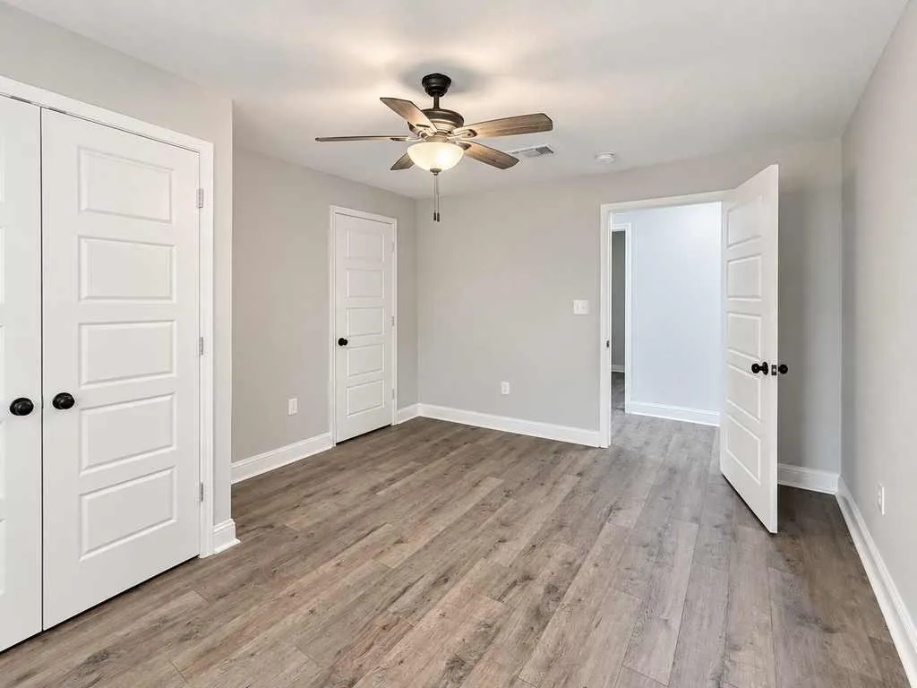 Unfurnished main home bedroom showing doors, closet access, and laminate flooring.
