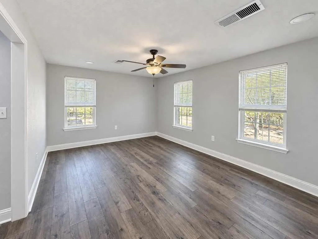 Unfurnished main home living room showing windows, flooring, and room layout.