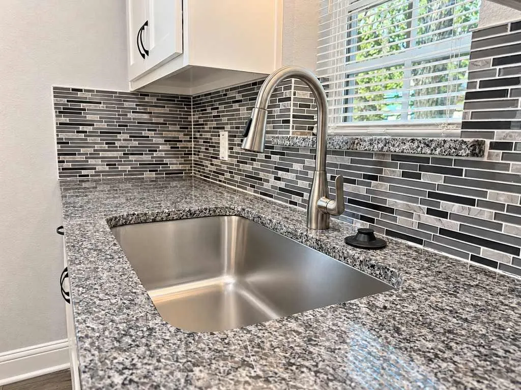 Close view of the main home kitchen sink, faucet, and tile backsplash.