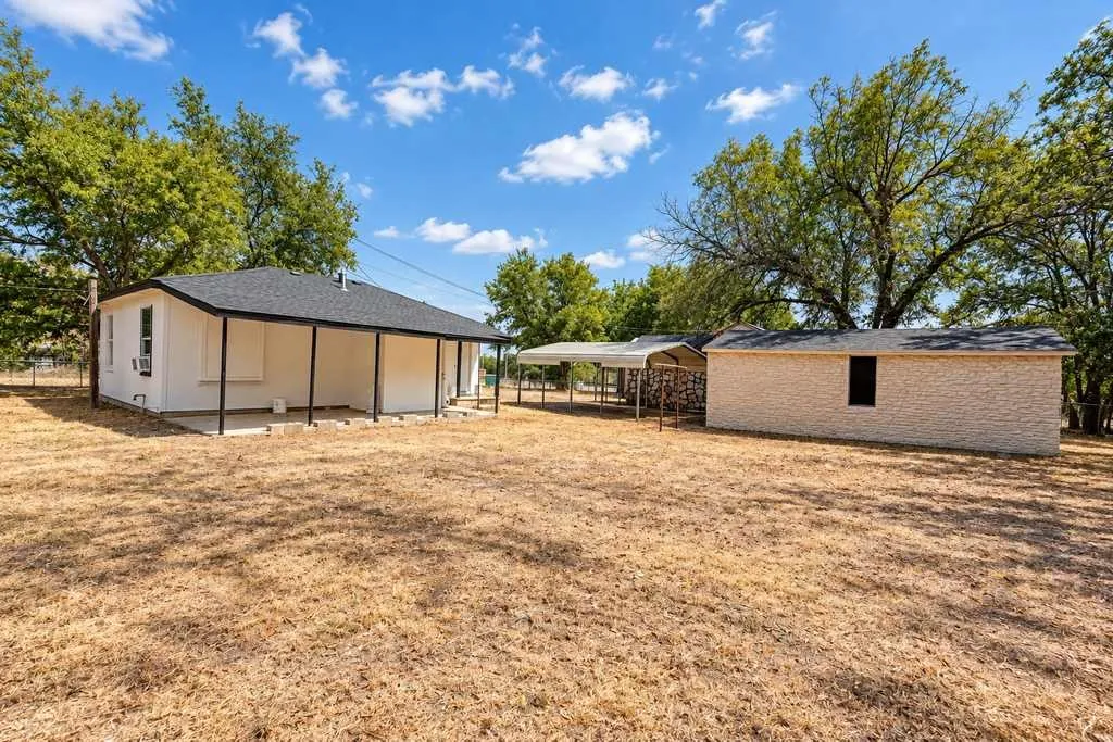 Yard view showing the second home, covered parking, and outbuildings.