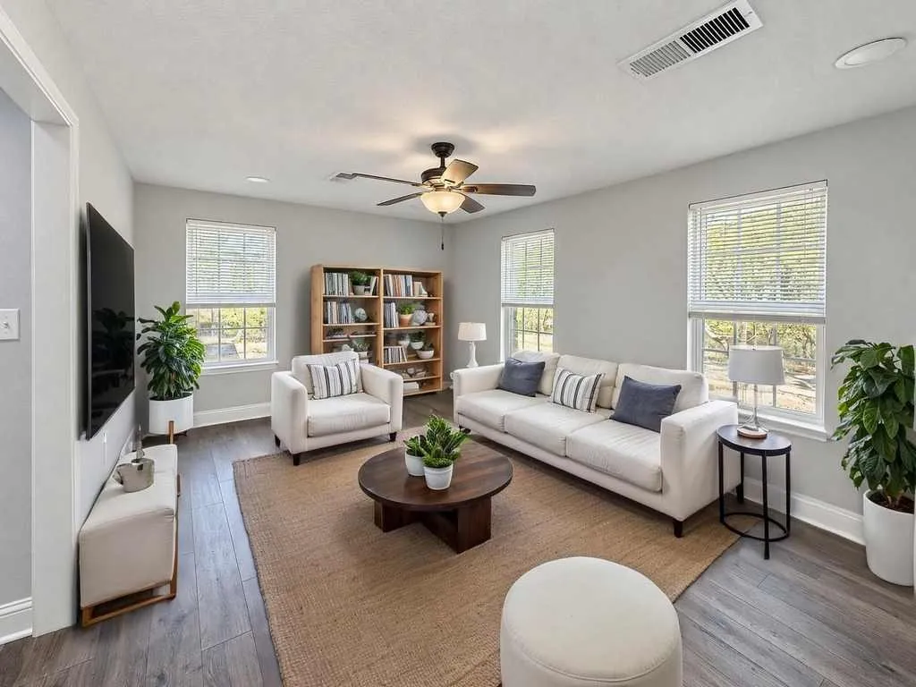 Main home living room with multiple windows and laminate flooring. Virtually staged.
