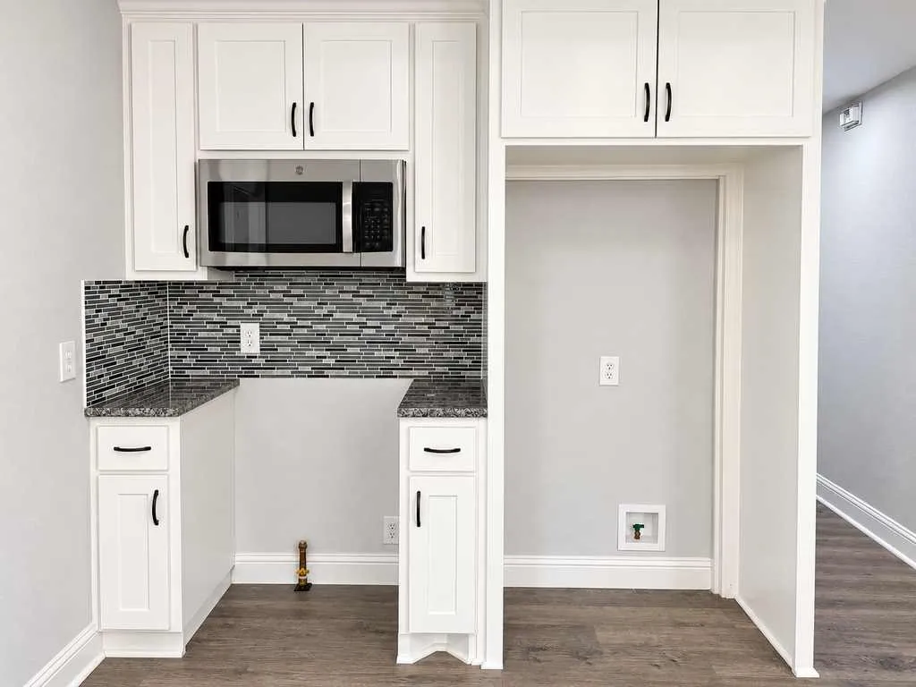 Main home kitchen cabinetry, microwave, and unoccupied appliance spaces.
