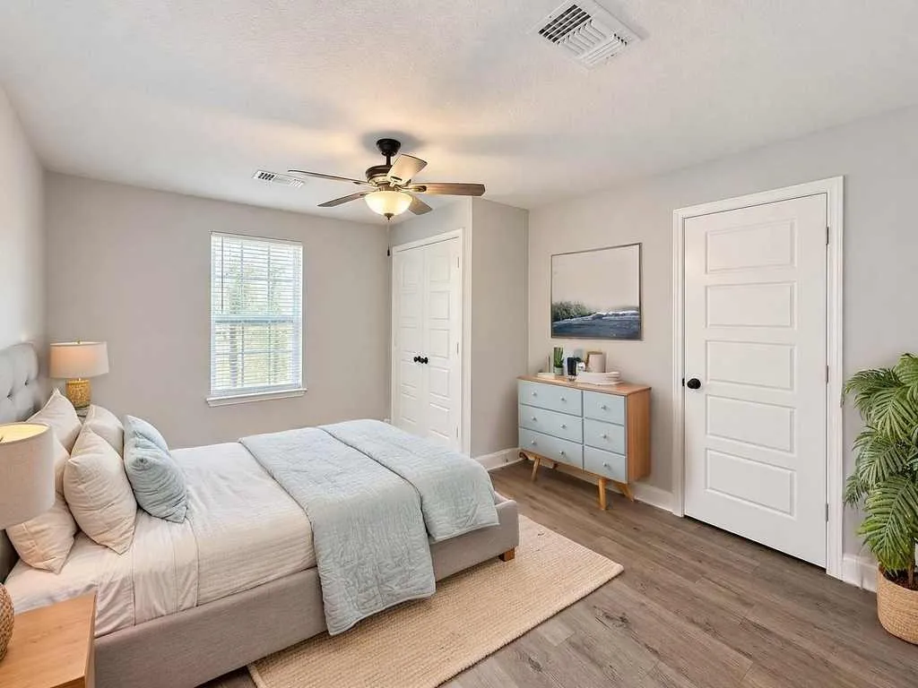 Main home bedroom with laminate flooring and a ceiling fan. Virtually staged.