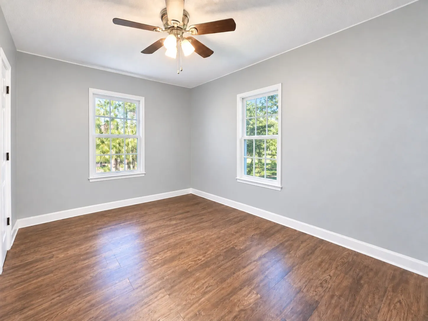 Additional second home bedroom with windows and wood-look flooring.