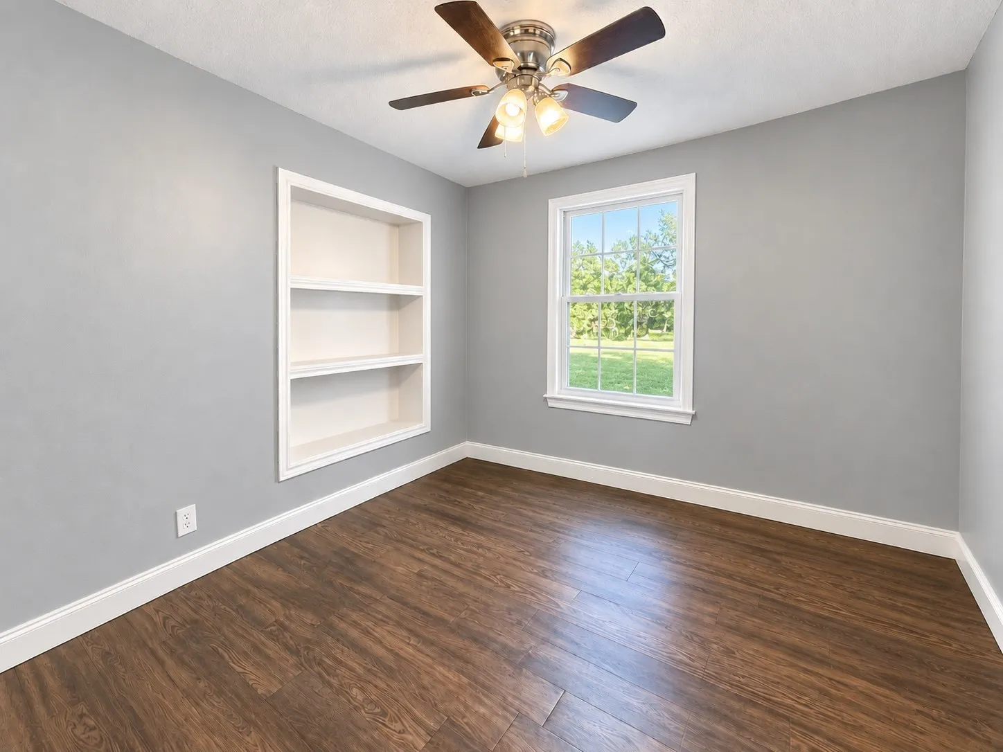 Second home bedroom with built-in shelving and a ceiling fan.
