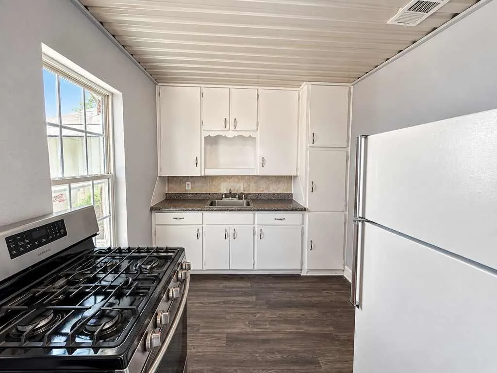 Second home kitchen showing cabinetry, a sink, a gas range, and a refrigerator.
