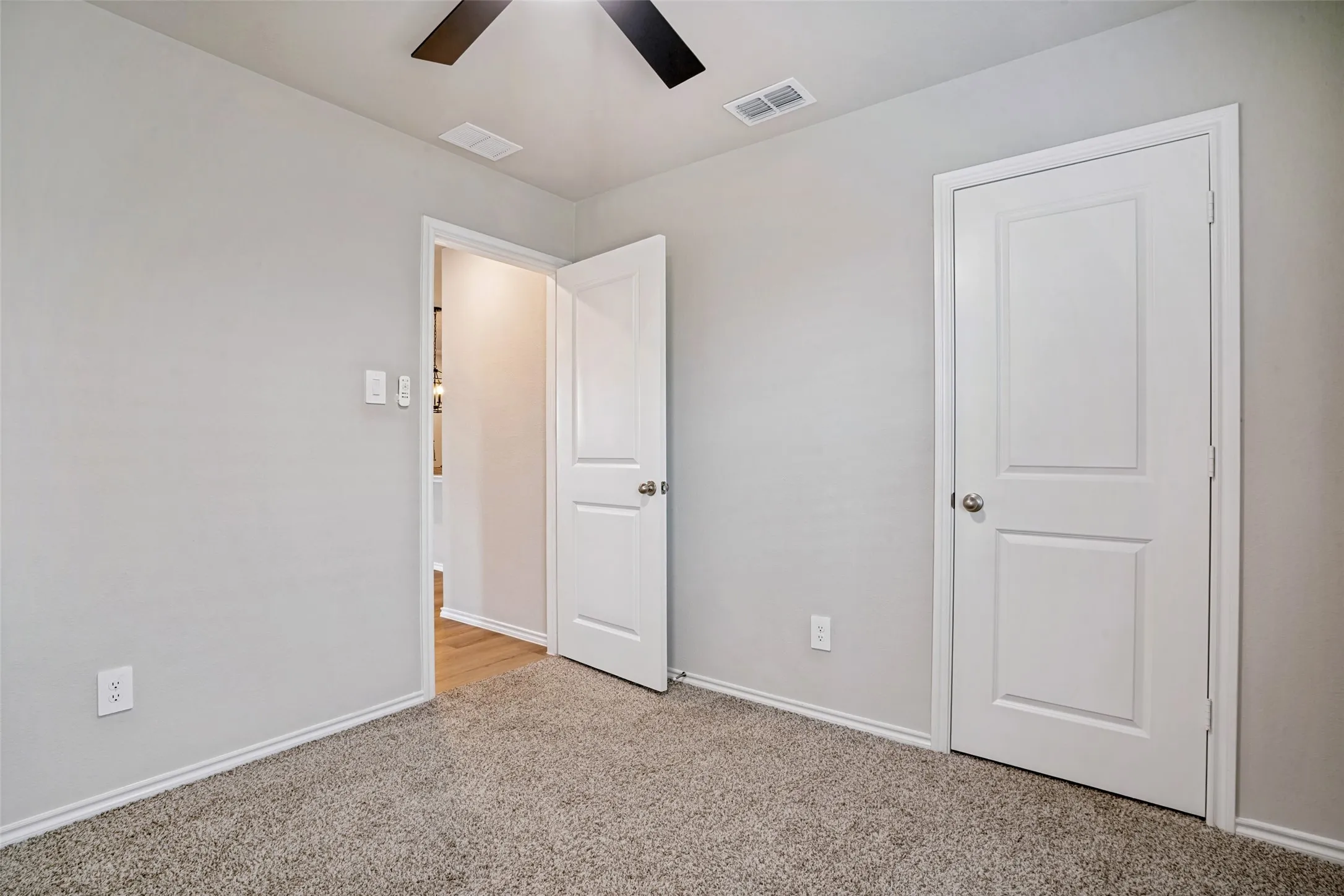 Plush carpeting, ceiling fan, and white paneled doors