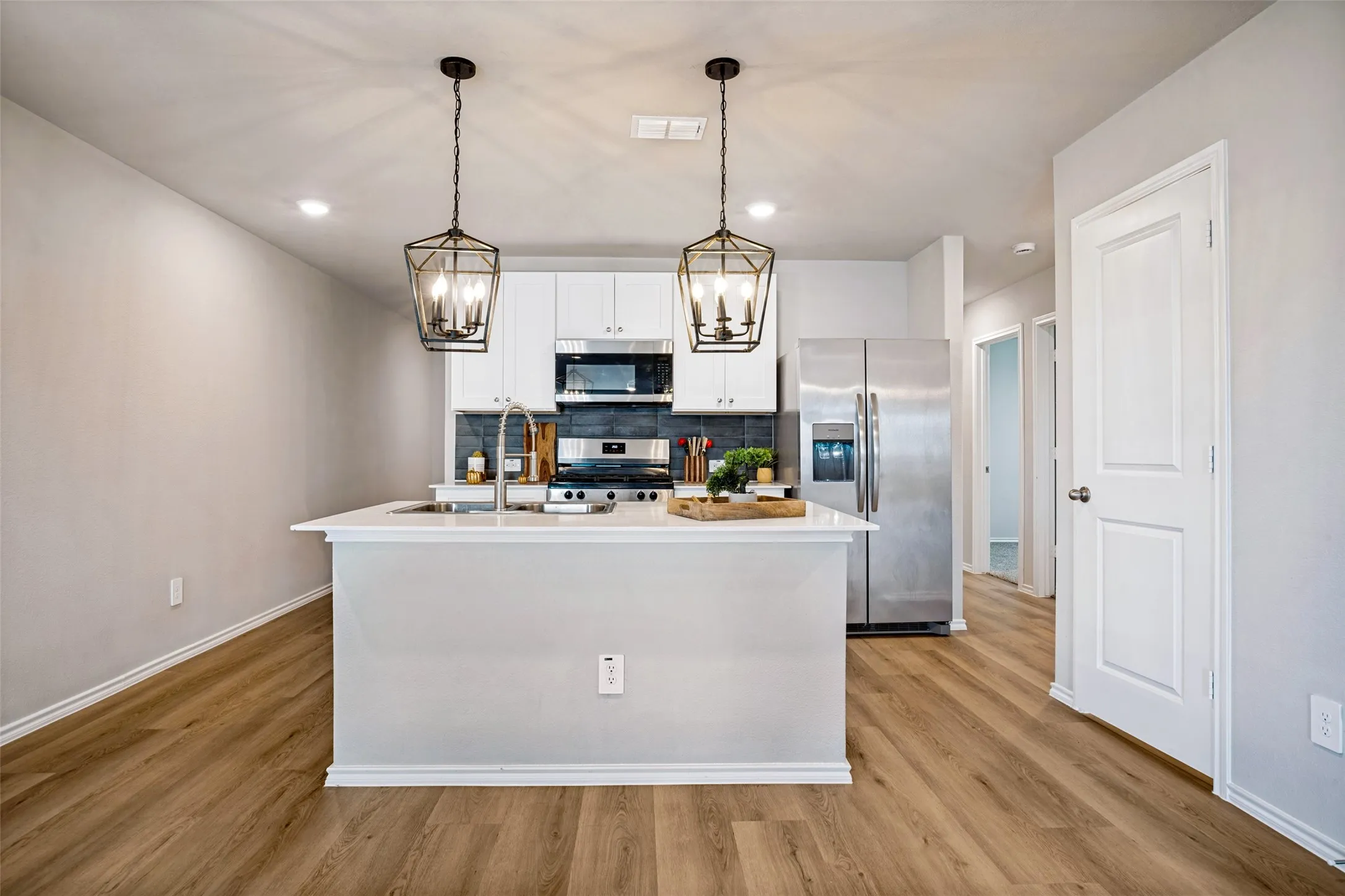 Kitchen featuring a center island, stainless steel appliances, wood-finish flooring, white cabinetry, and recessed lighting