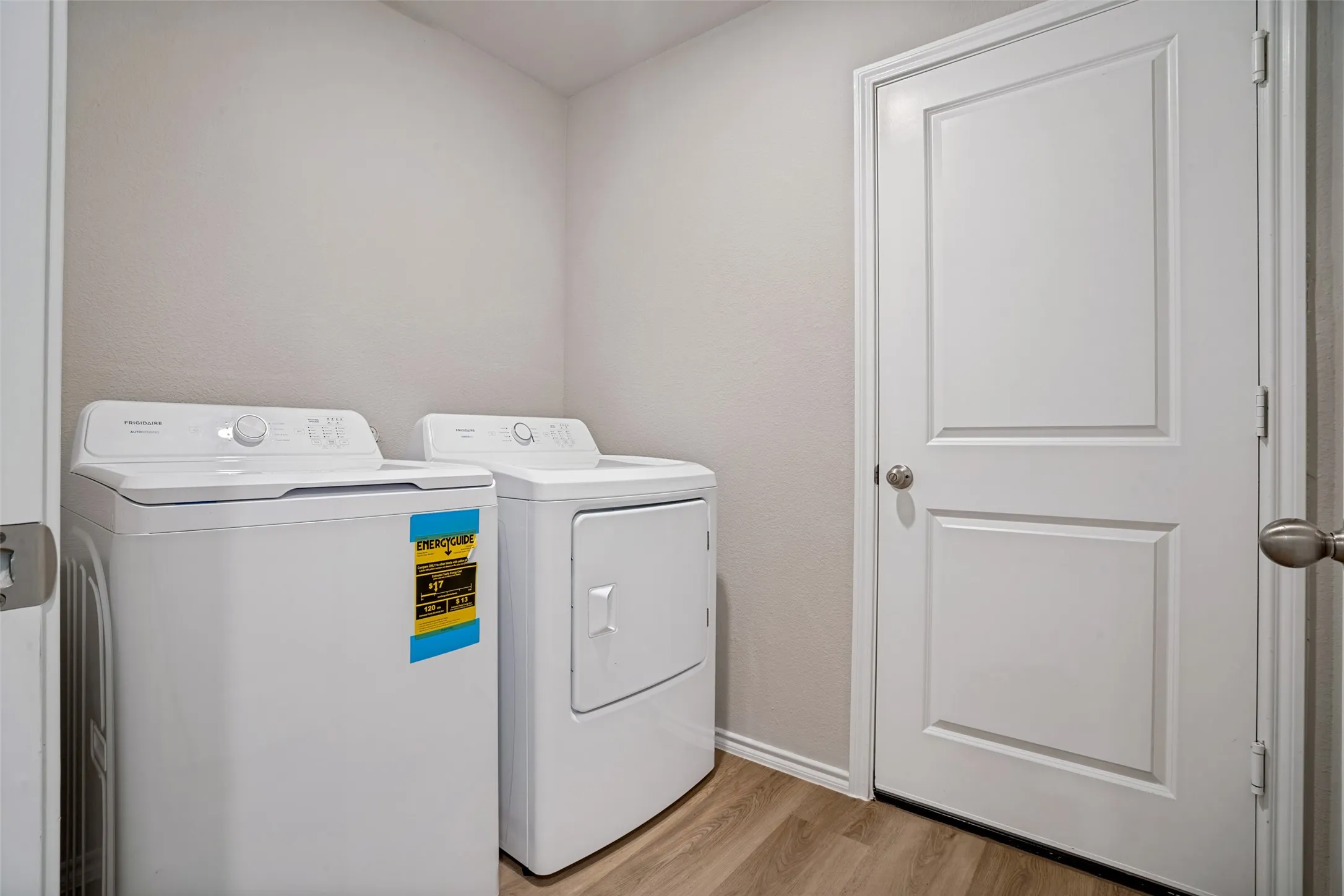 Dedicated laundry area featuring a built-in washer and dryer, wood-finish flooring, and a paneled door