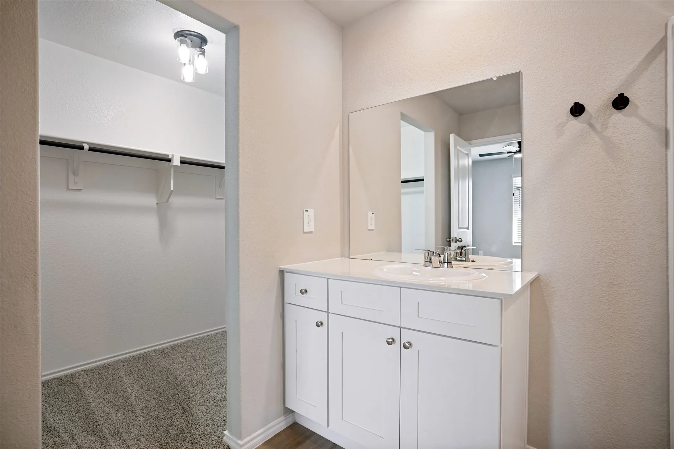 White vanity with dual sinks, chrome faucets, and an expansive mirror