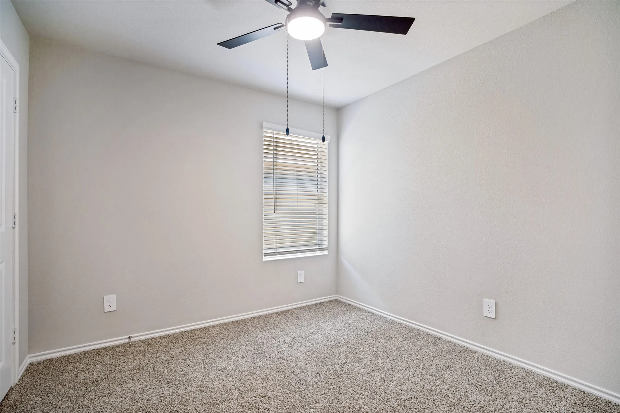 Bedroom featuring neutral-toned walls, carpet flooring, a window with blinds, and a ceiling fan with integrated lighting