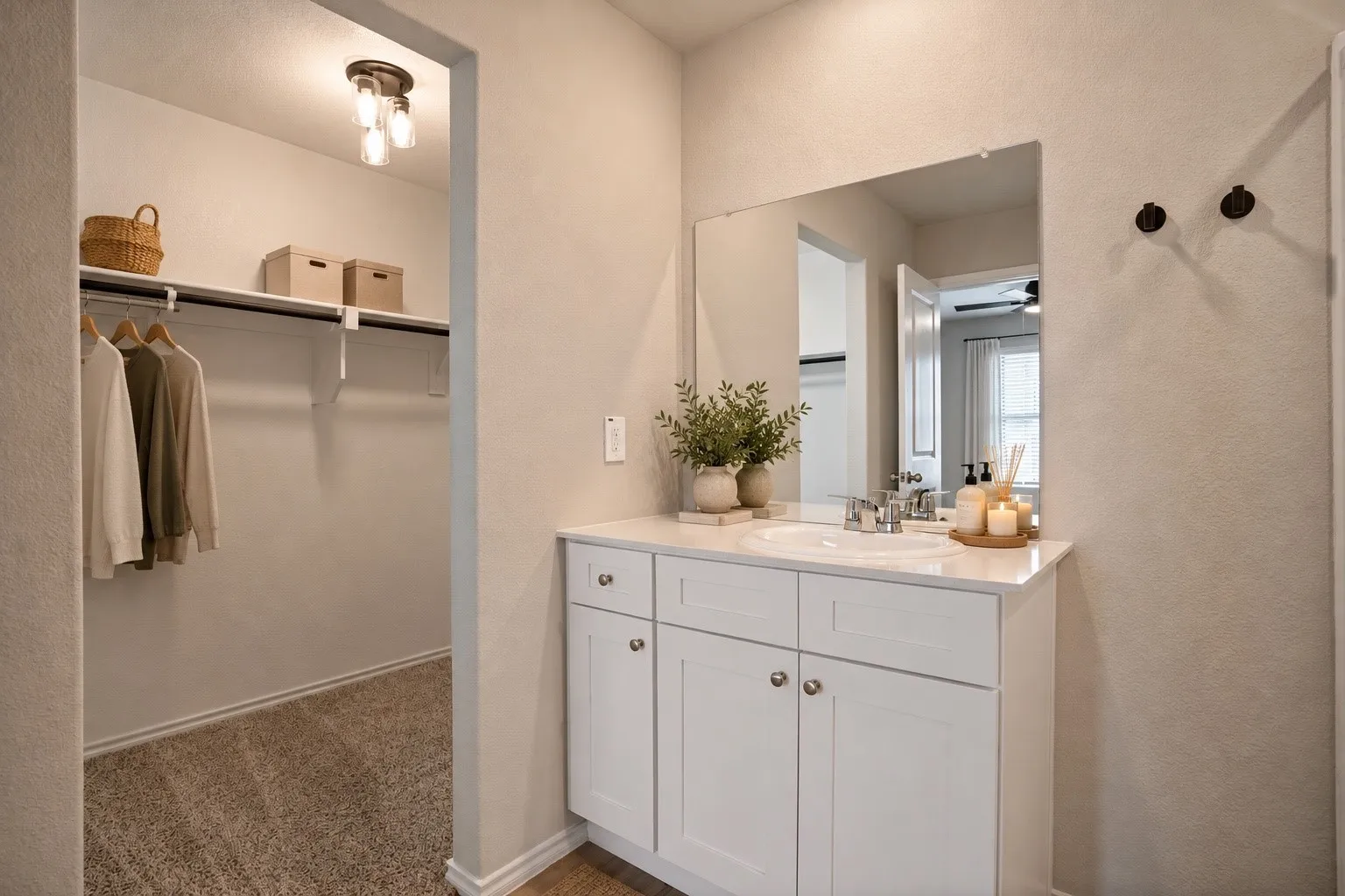 White vanity with a single basin sink, silver-finish faucet, and an expansive mirror