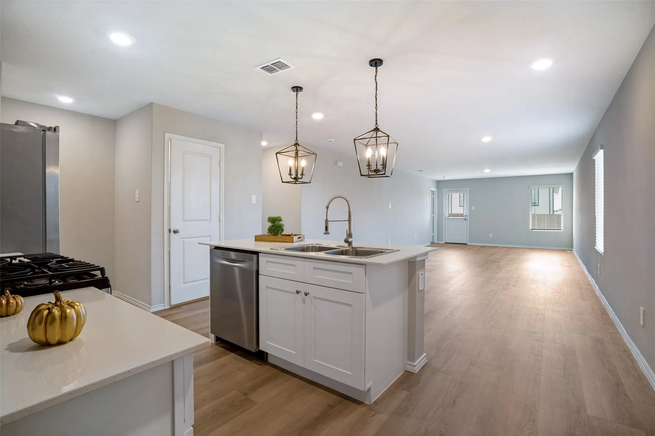 Kitchen featuring an island with double sink, white cabinetry, stainless steel dishwasher, recessed lighting, and wood-finish flooring