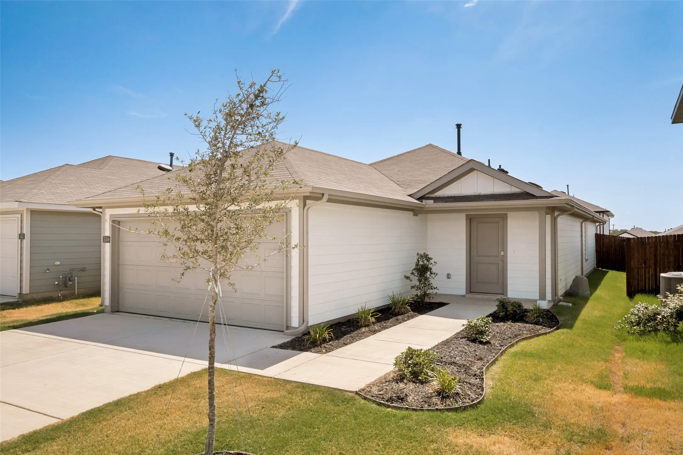 Single-story exterior with a two-car garage, concrete driveway, and a landscaped front walk