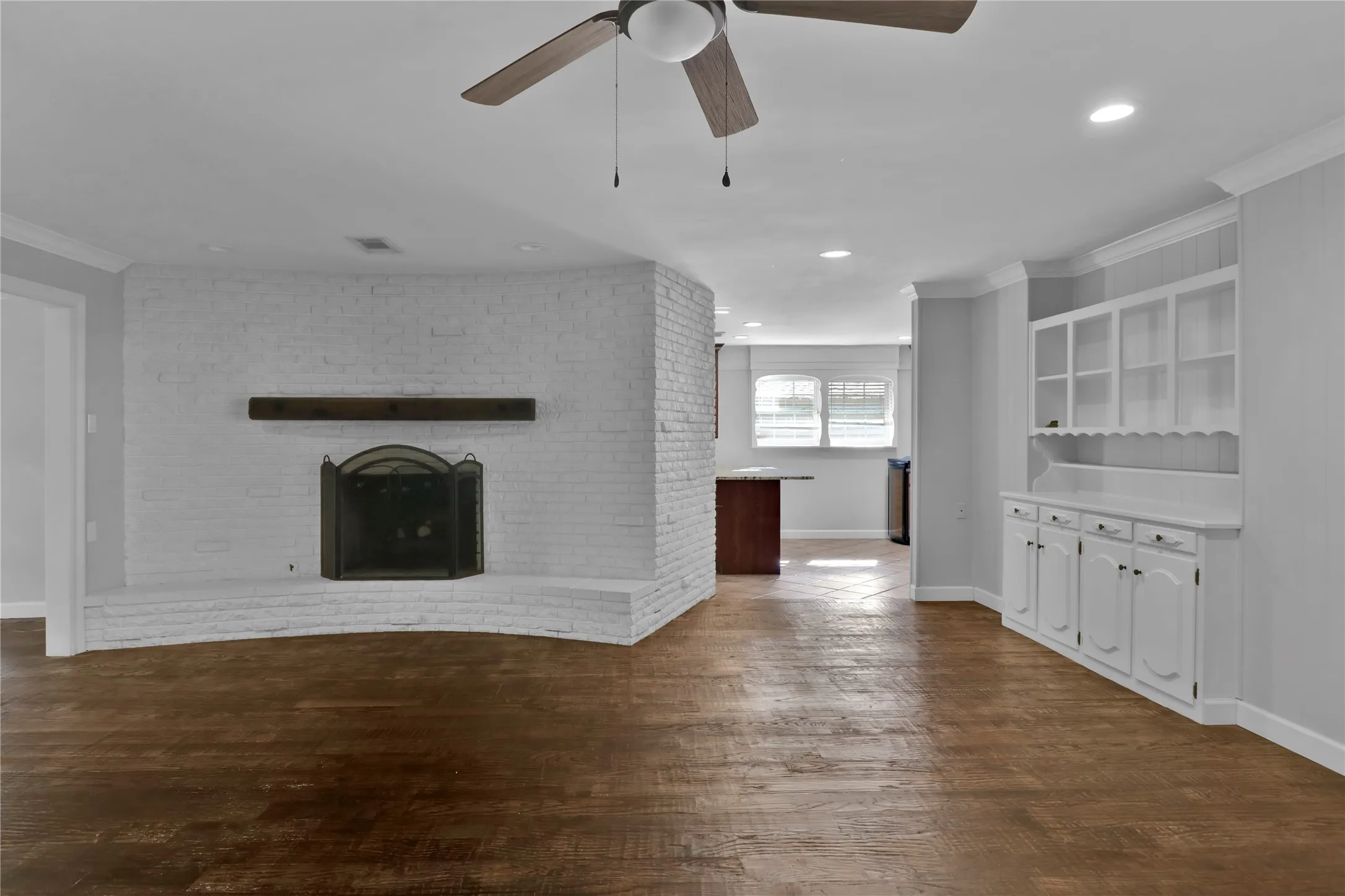 Family room leading to kitchen and breakfast area with fireplace and mantel.